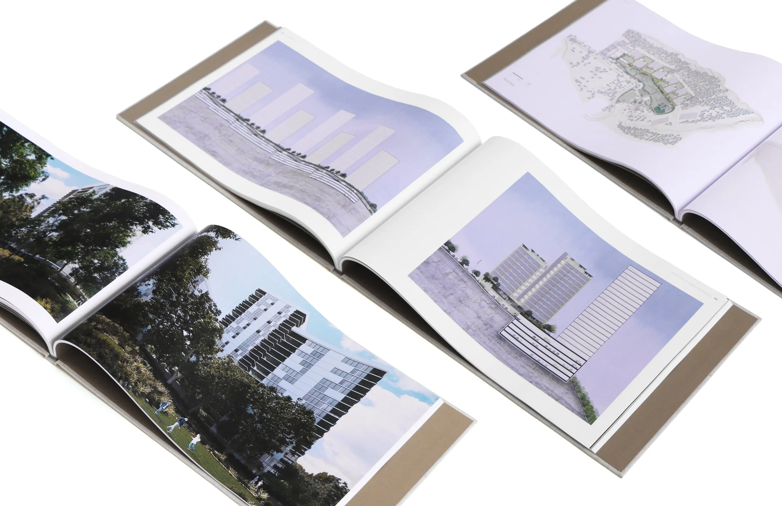 Open architectural design books and blueprints featuring building plans, elevation views, site layouts, and color photographs of the buildings and surrounding environment.