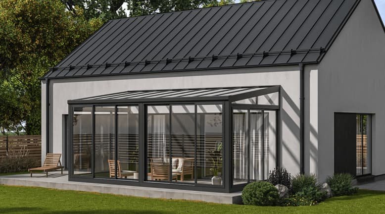 Moderne witte huis met een glazen serre op de patio, omgeven door groene tuin en bomen.
