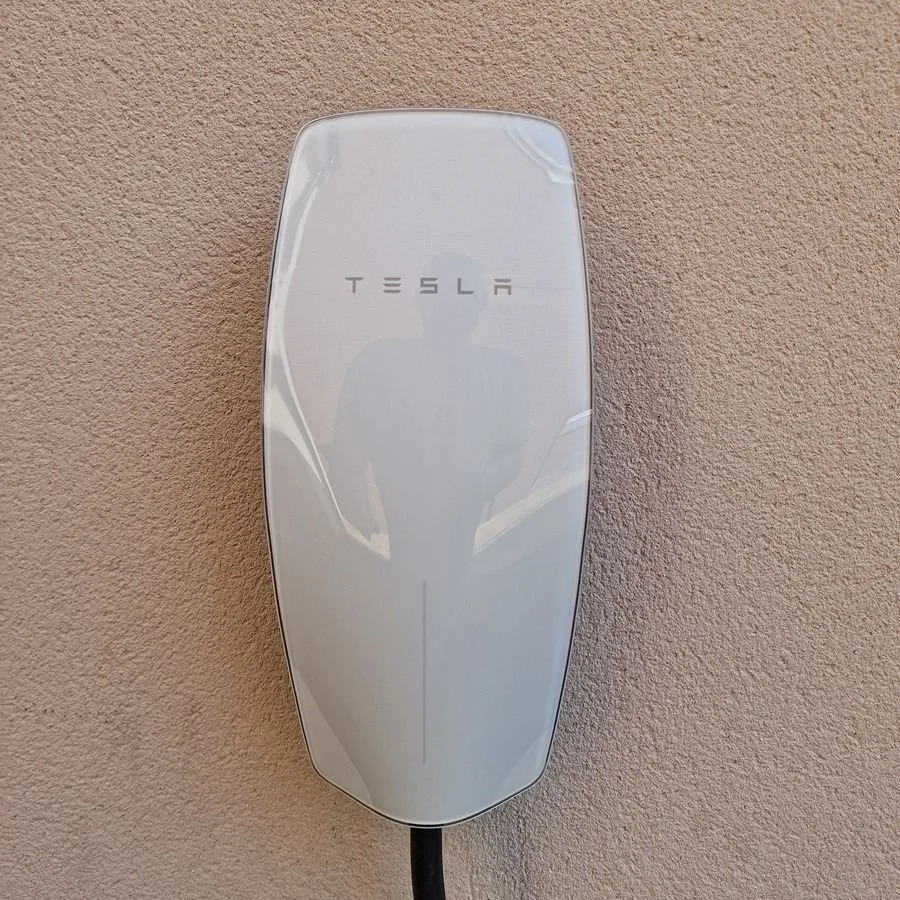 Tesla electric vehicle charging station mounted on a beige wall.
