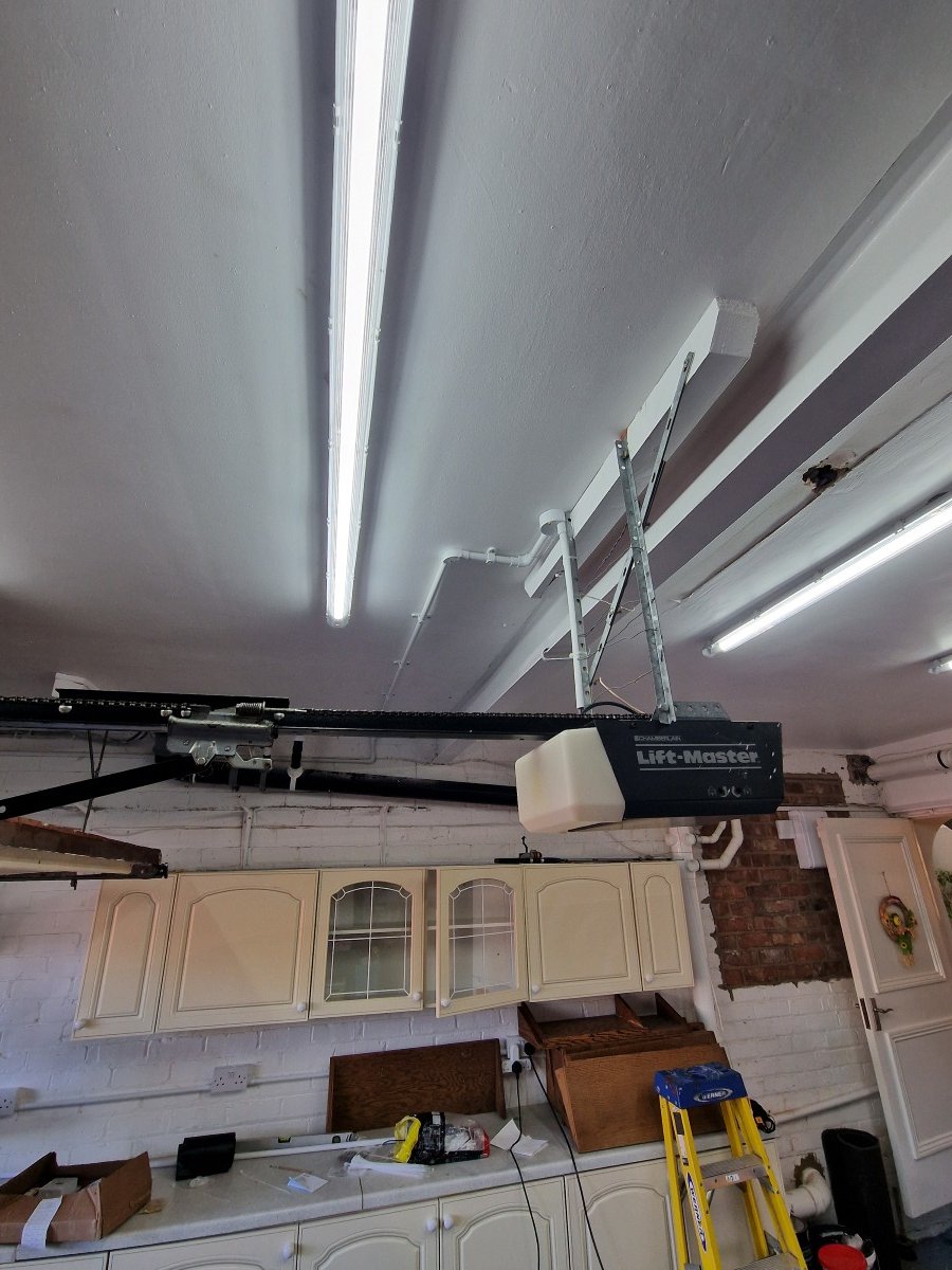 Garage ceiling with an open garage door opener and ladder, kitchen cabinets and countertop below.