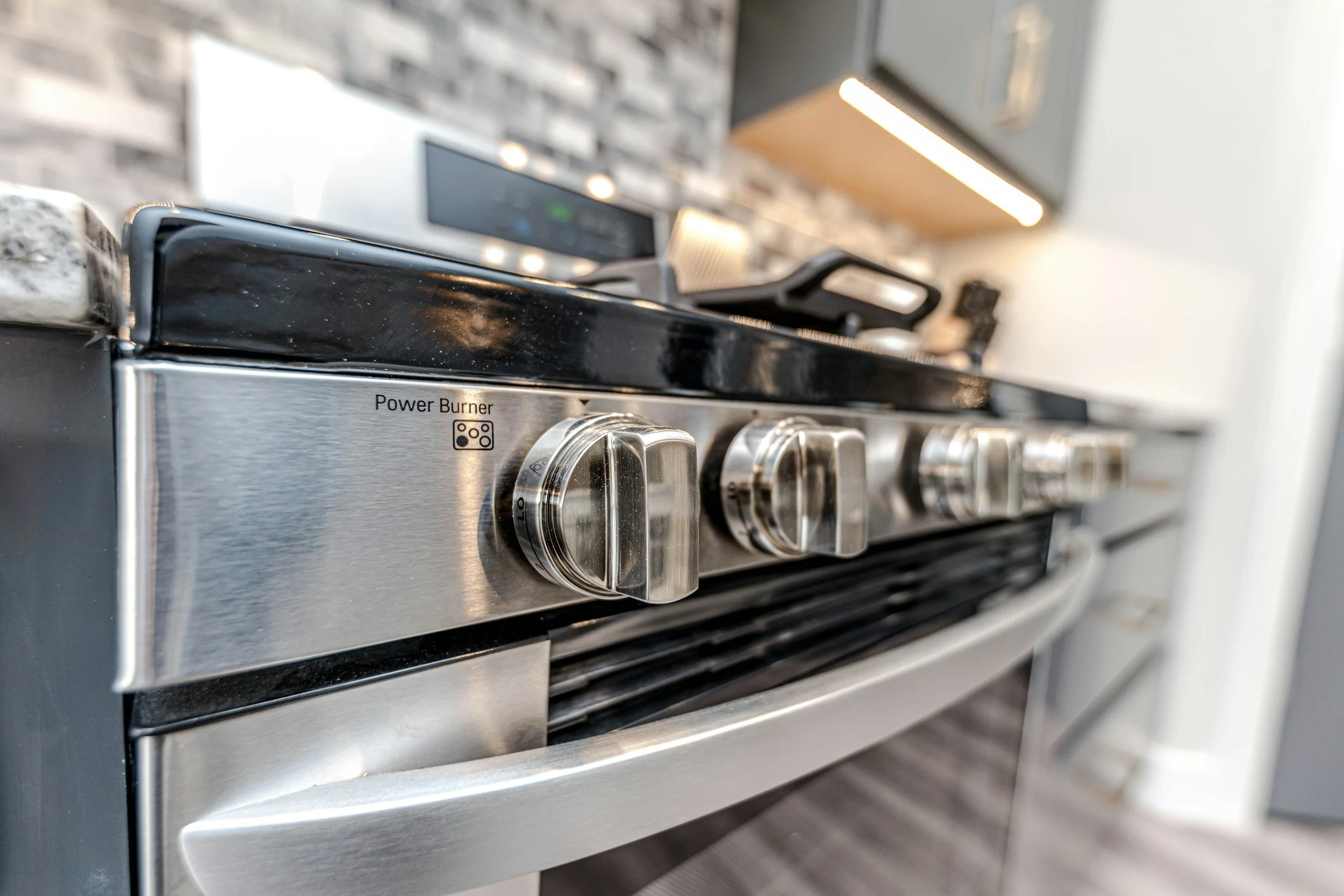 Close-up view of a stainless steel gas stove with black grates and metallic control knobs.