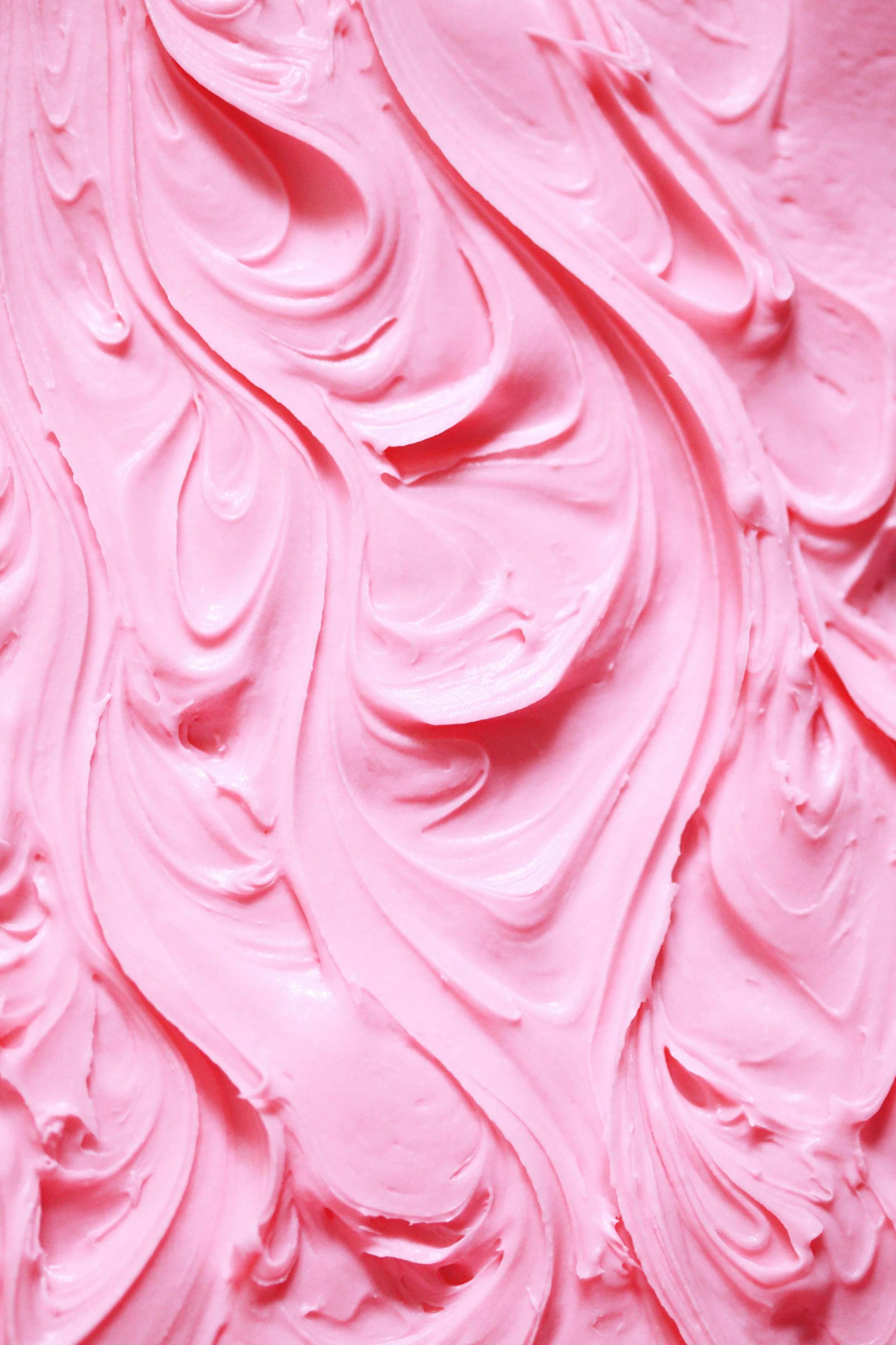 Close-up of pink swirled frosting with a smooth, creamy texture.