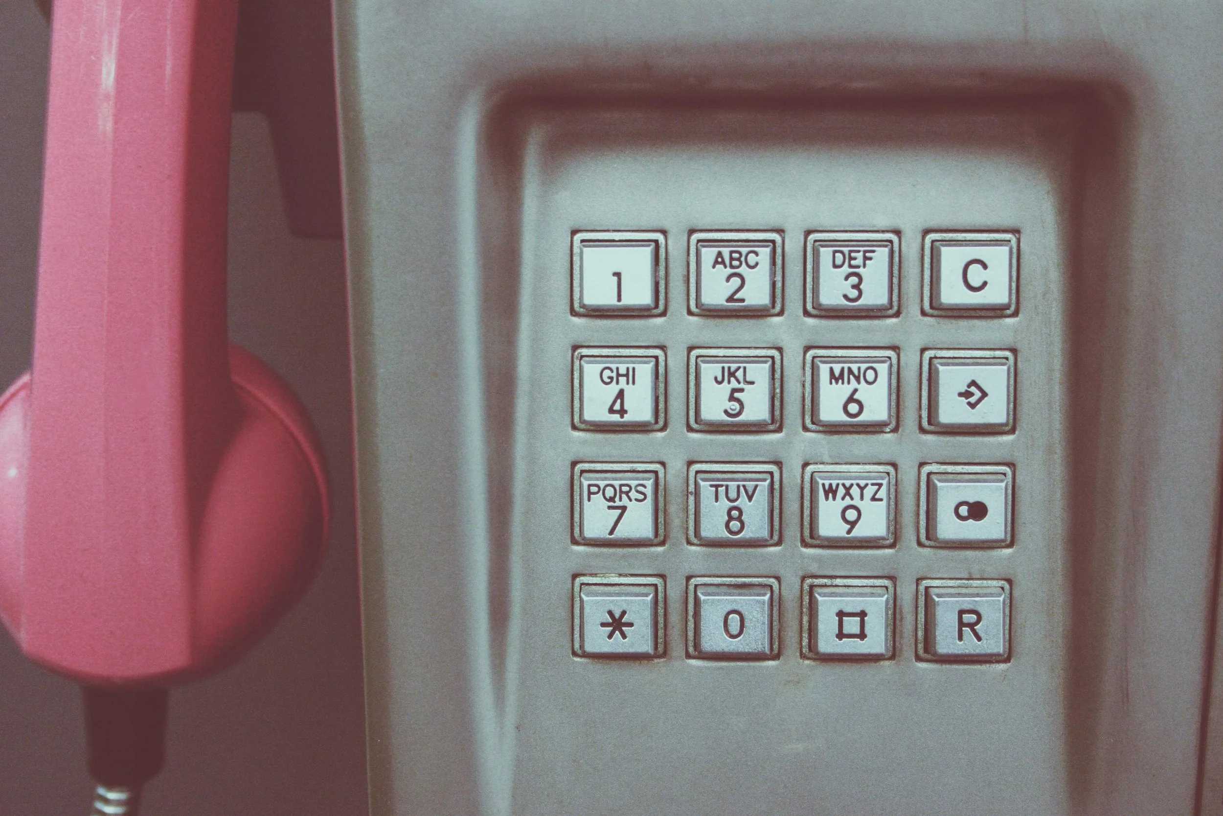 an old metal payphone with a pink handle
