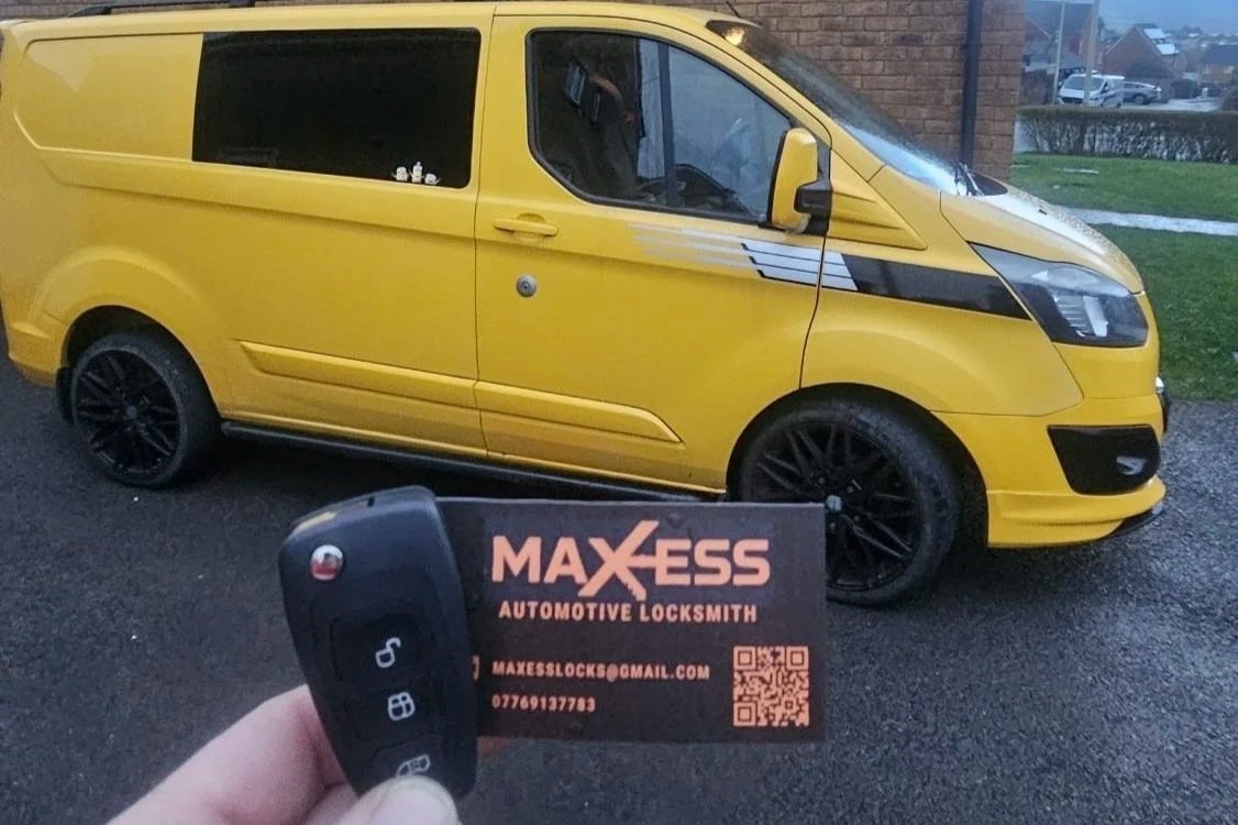 A yellow van parked on the street with a business card and remote key fob in the foreground.