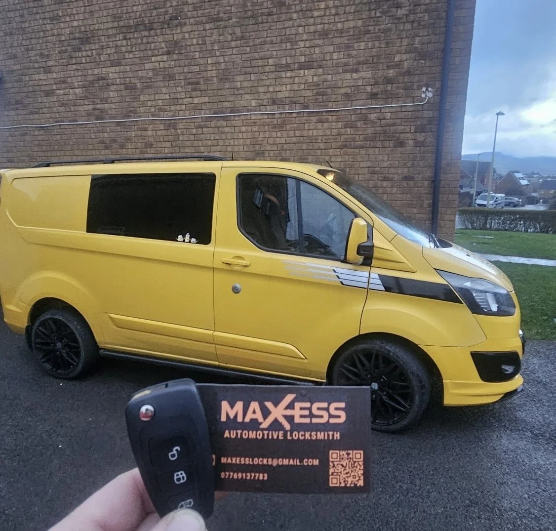 A yellow van parked on the street with a business card and remote key fob in the foreground.