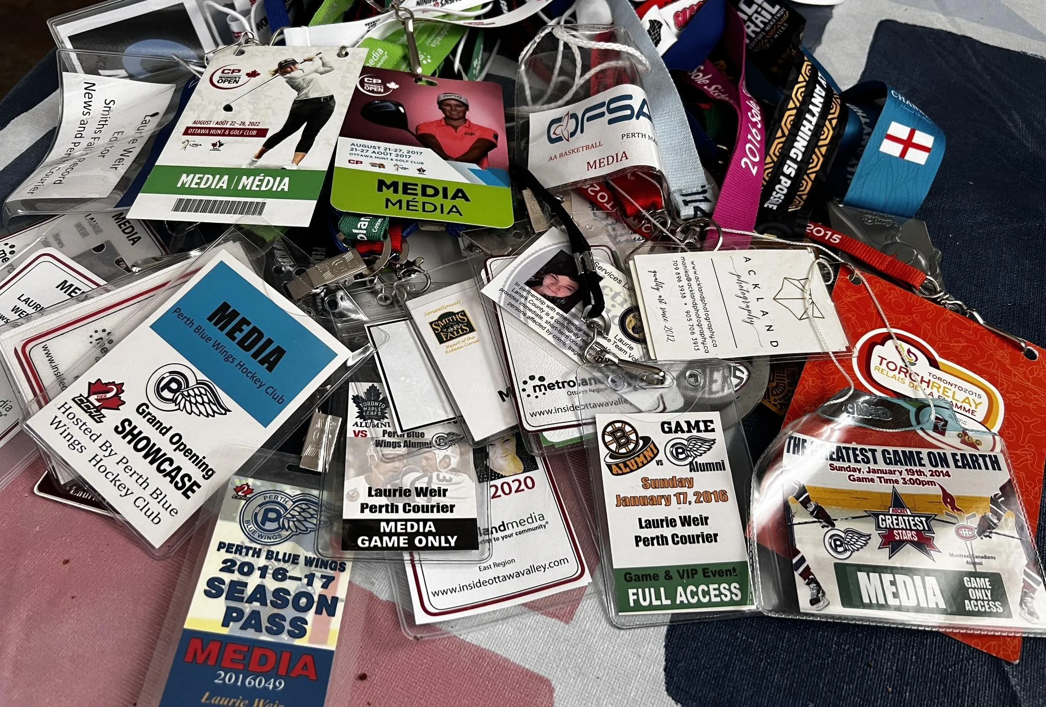 A pile of various media passes, tickets, and lanyards for different events, including sports games, hockey, and media access.