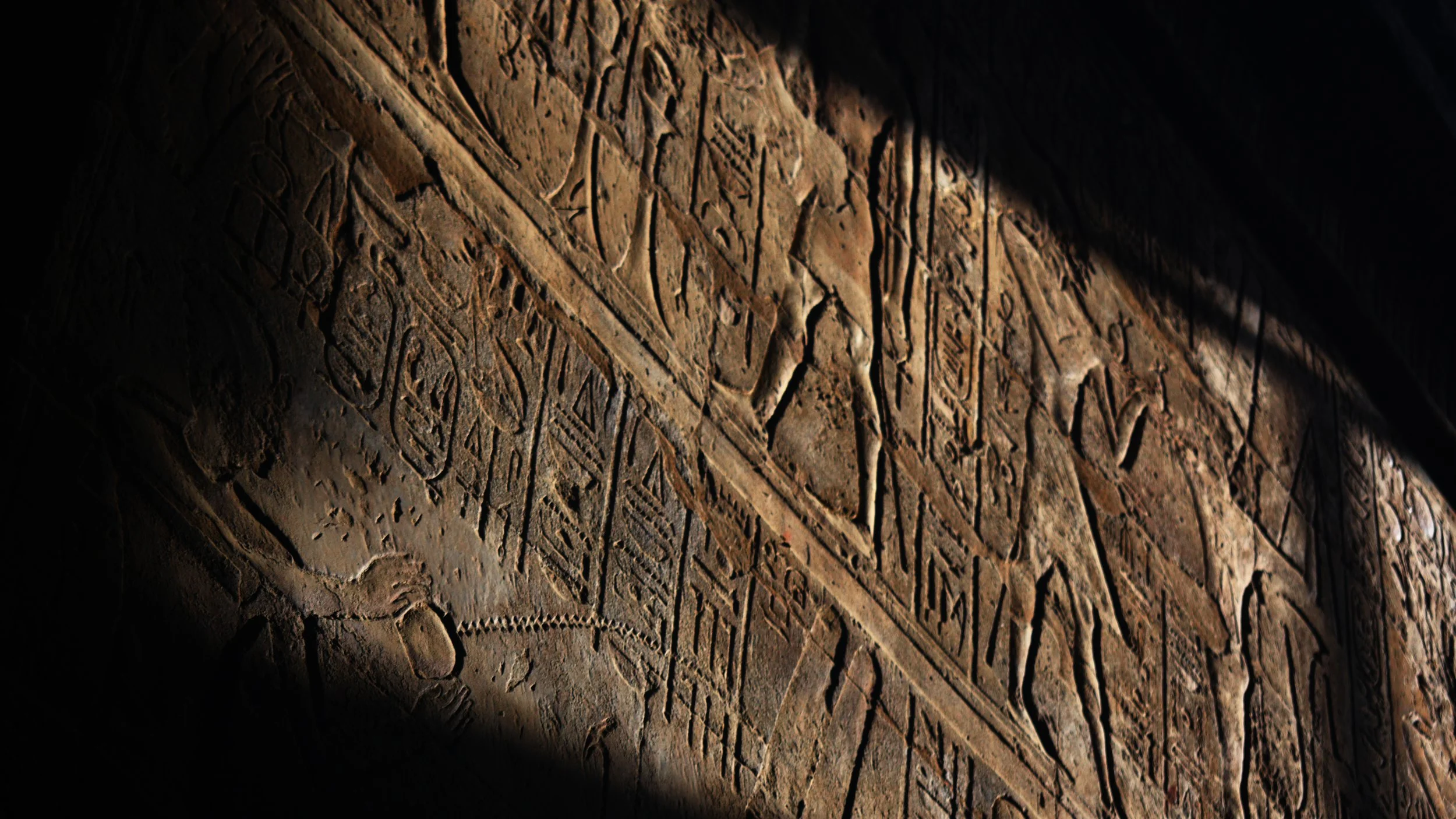 Egyptian heiroglyphs on wall in shadow