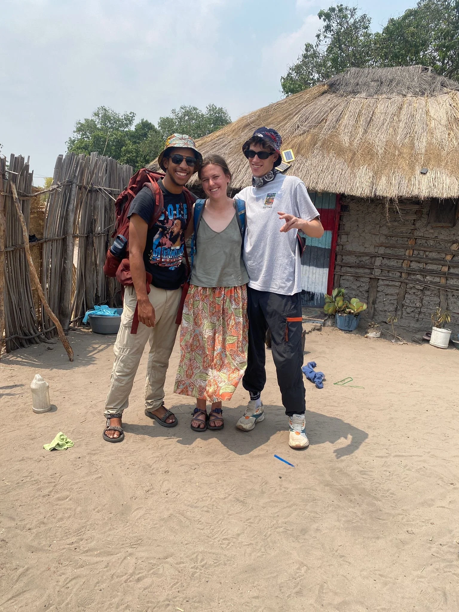 Three friends posing outside a village house