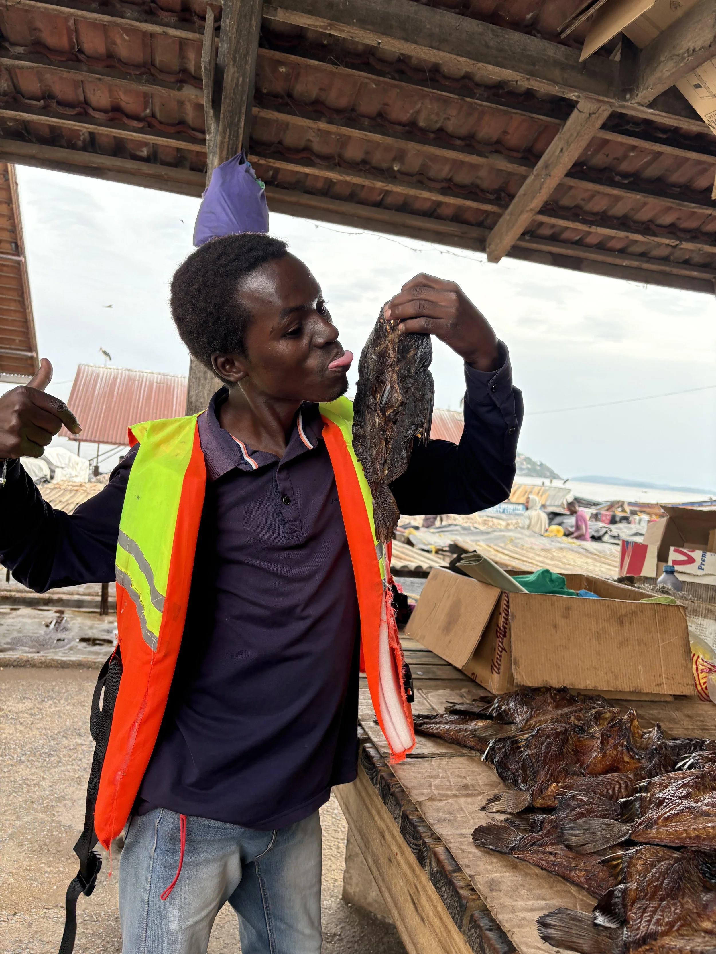 Tour guide sticks tongue out to taste dried fish at the market