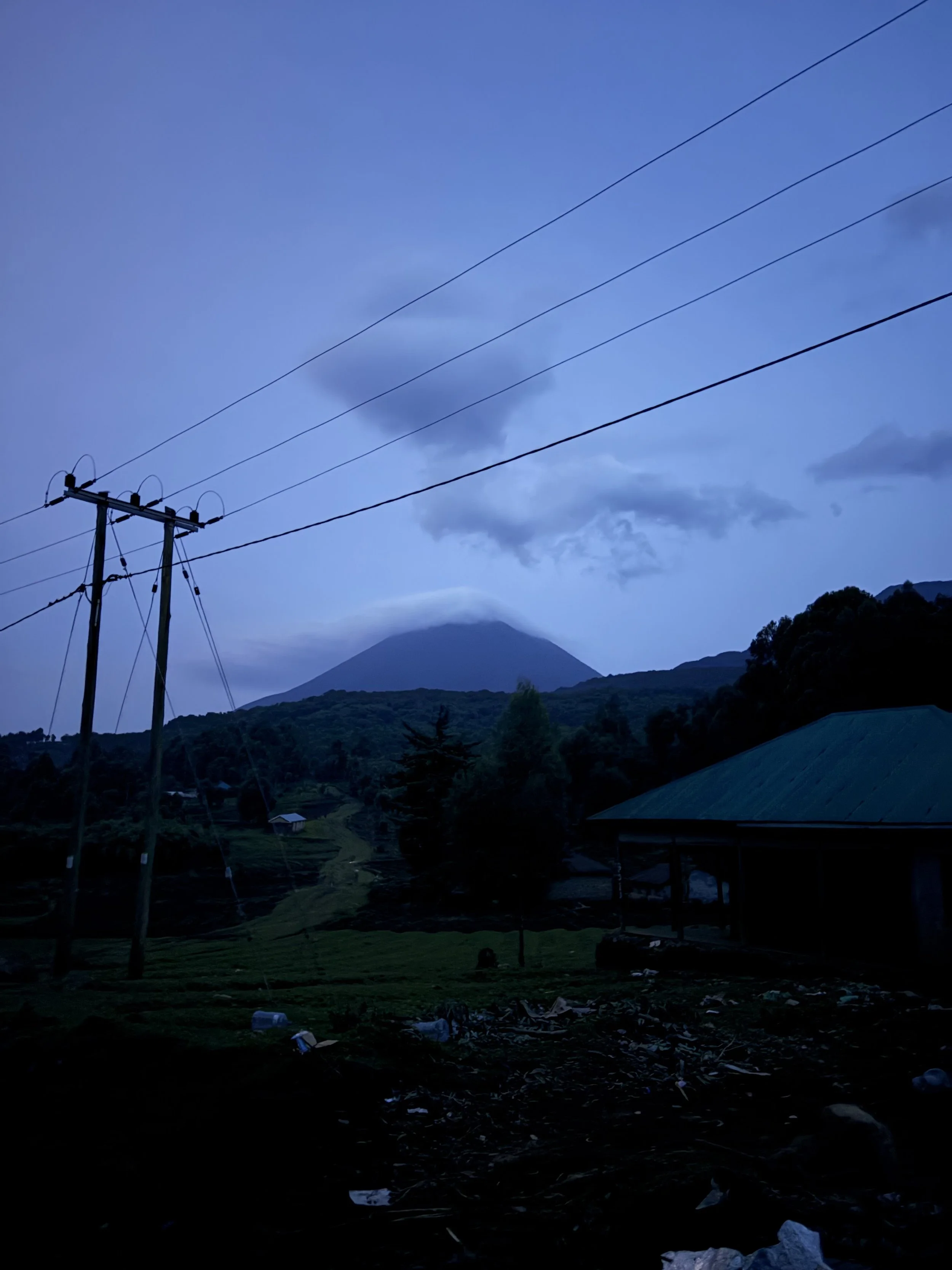 Mount Sabyinyo seen at night from Mgahinga National Park, with low clouds covering the summit before the hike.