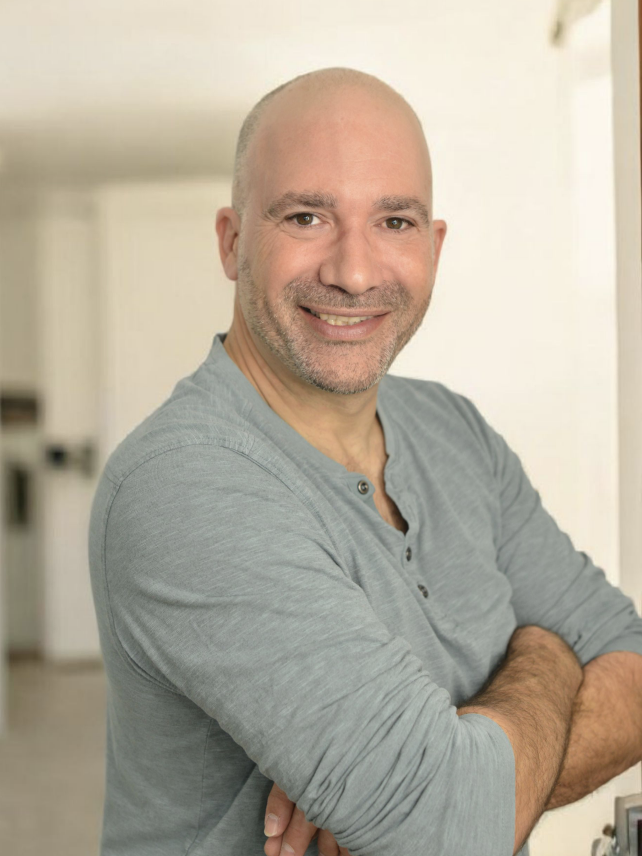 Un homme souriant artisan serrurier dépanneur pour sécuriclef gironde, bras croisés, dans un intérieur lumineux.