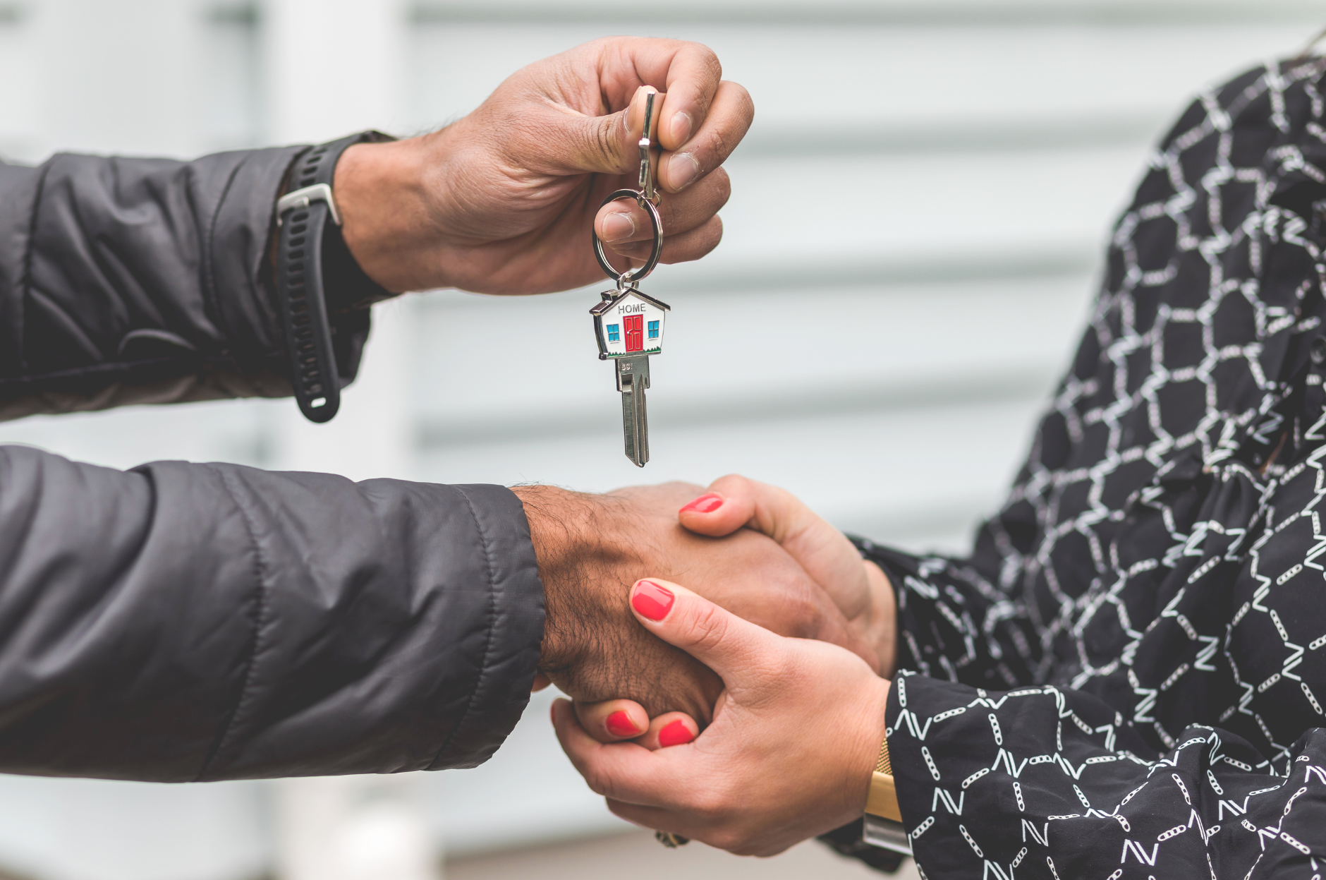 Deux personnes se serrent la main, l'une d'elles tient une clé avec une maison en forme de porte-clés.