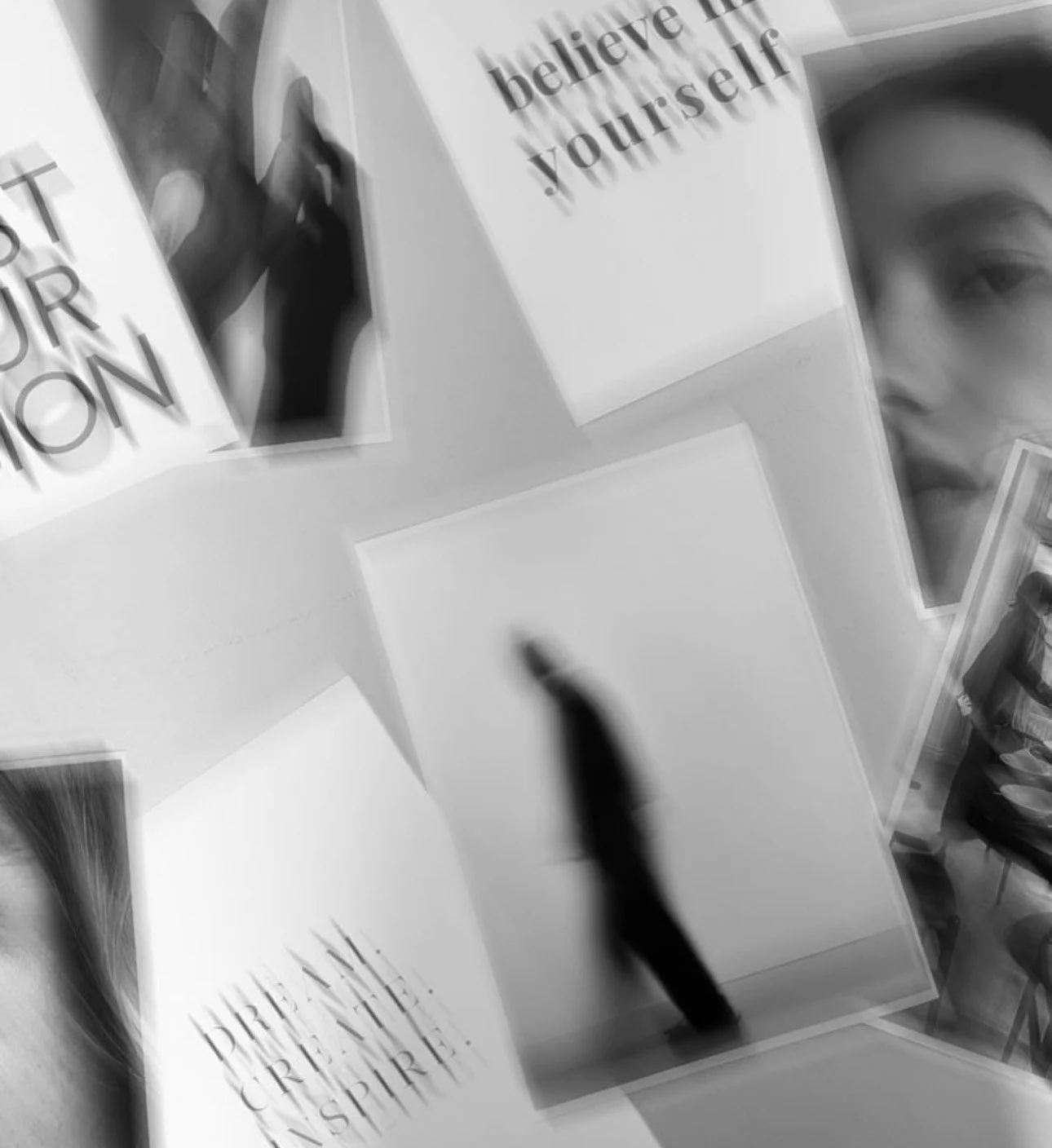Black and white photo of several open notebooks or magazines with inspirational quotes and images, including one that says 'believe in yourself' and another with a partially visible face of a woman.