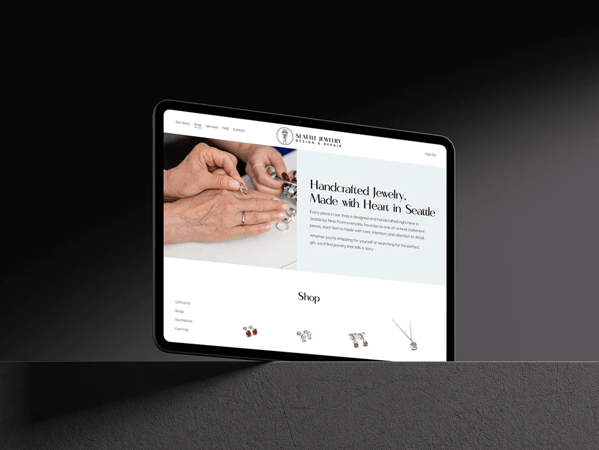 A tablet displaying a jewelry shop website on a dark desk surface. The website features handcrafted jewelry with a section showing various jewelry pieces like earrings and necklaces.