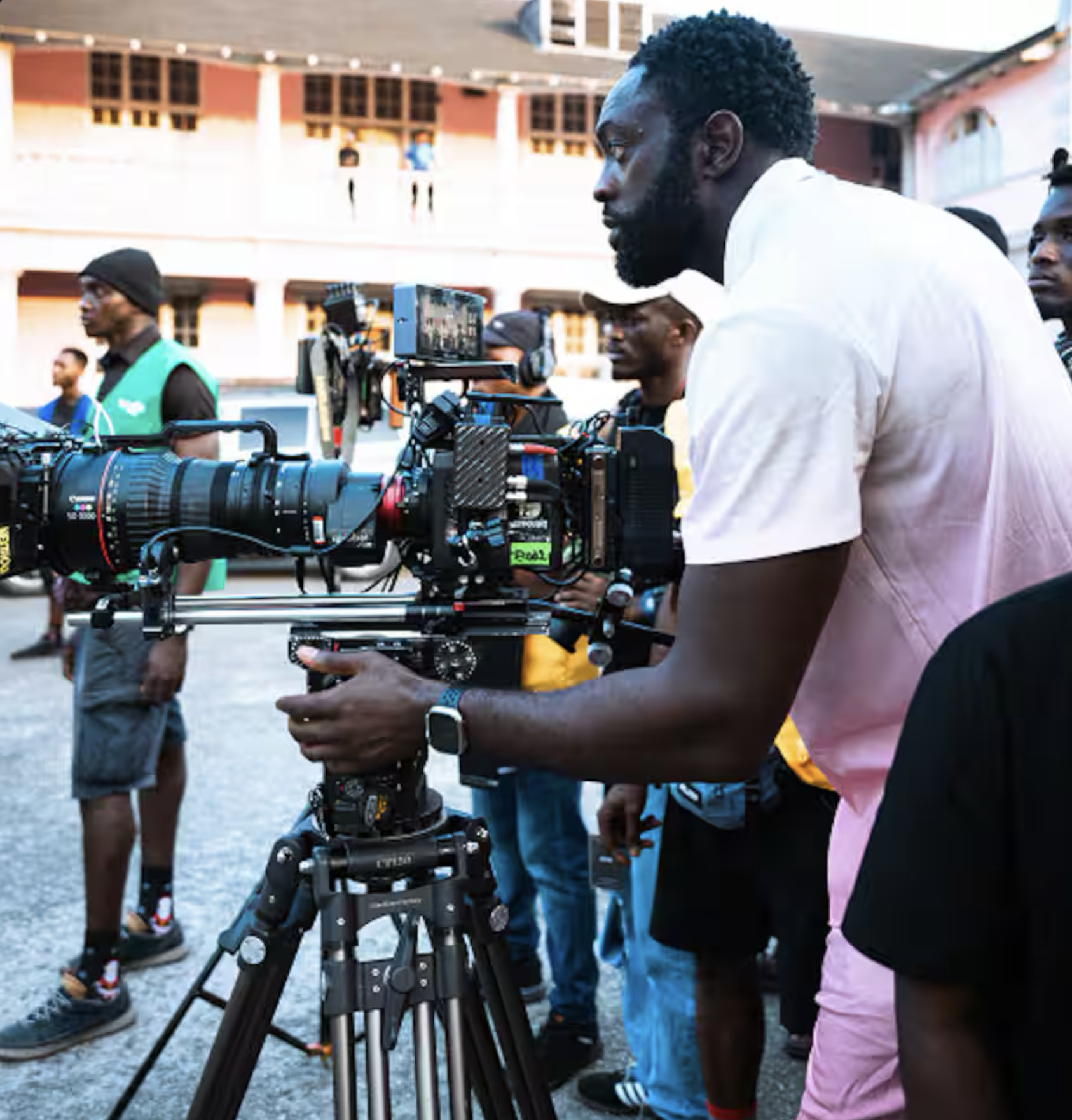 A layered cake with white frosting and fruit filling on a green cake stand, slices on plates, and glasses of rosé wine on a white tablecloth.