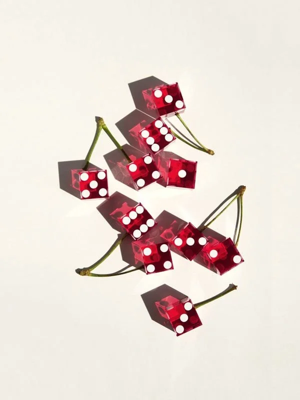 Multiple red transparent dice with white dots, arranged artistically on a white surface with shadows.
