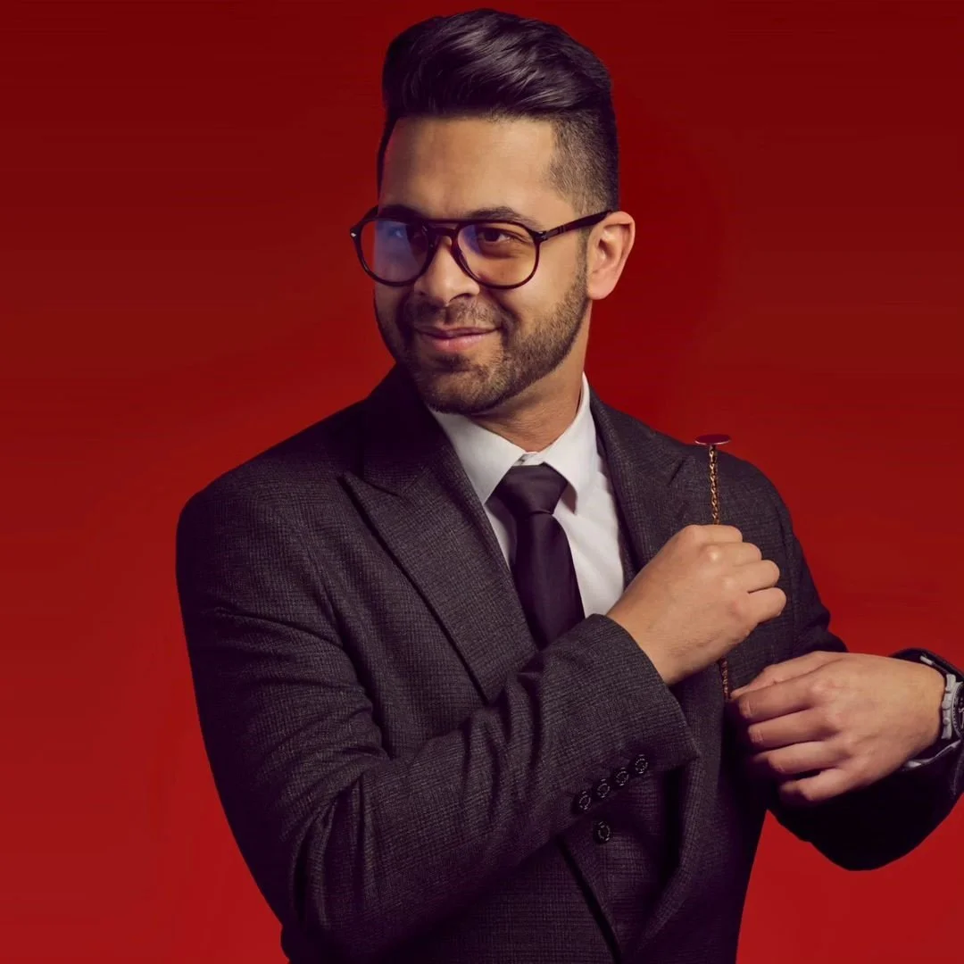 A man in a suit and glasses holding a Jewish menorah against a red background.