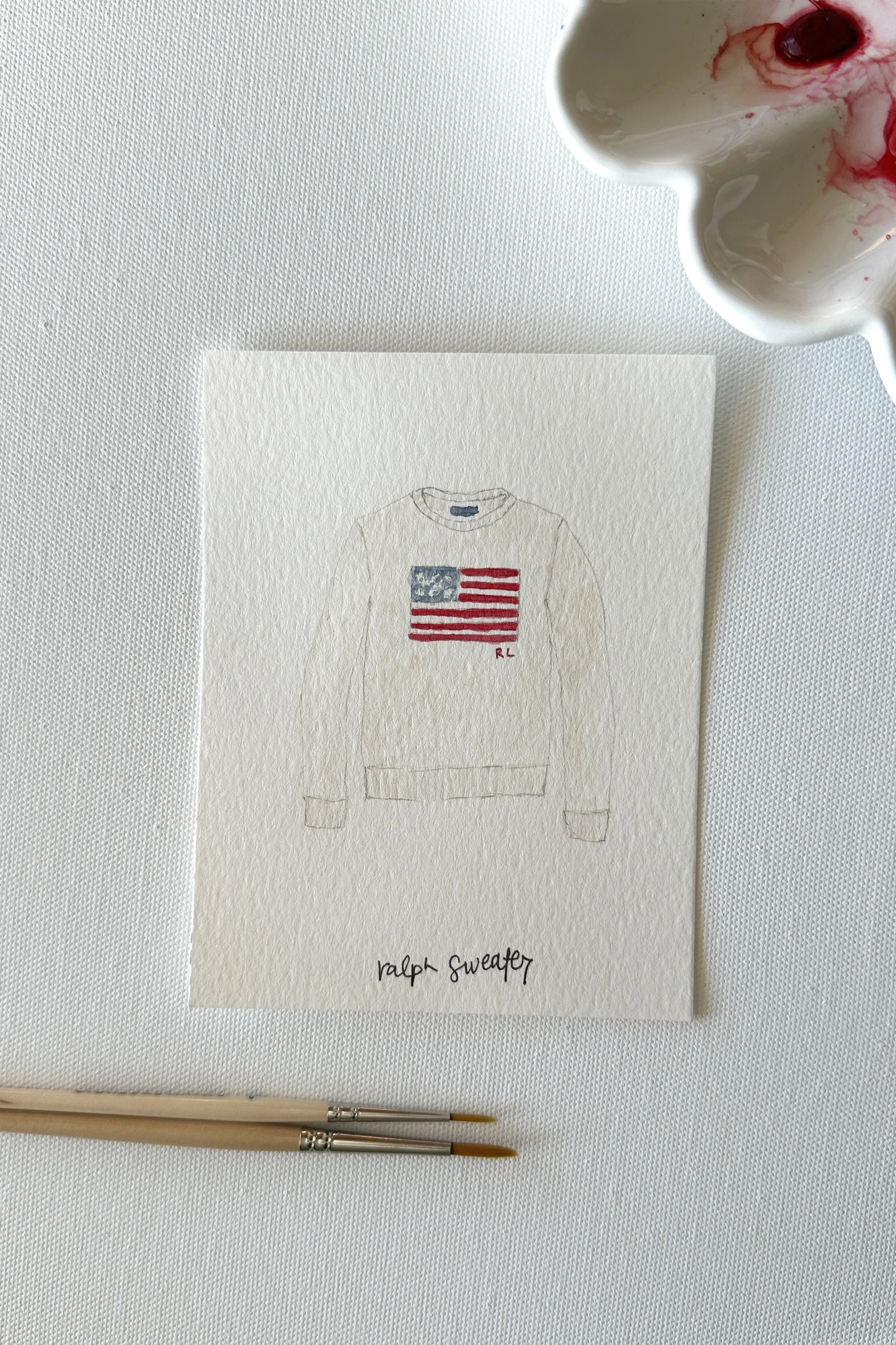 A watercolor of an American flag sweater, painted for the July Independence Day theme.