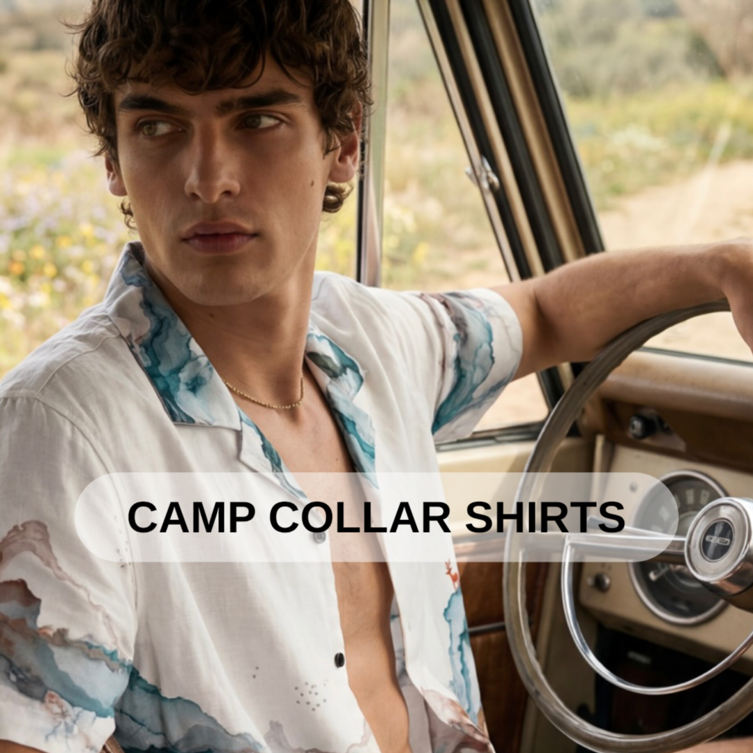 A young man sitting inside a vintage car, wearing an open camp collar shirt with a watercolor-style pattern, looking to the side with a neutral expression.