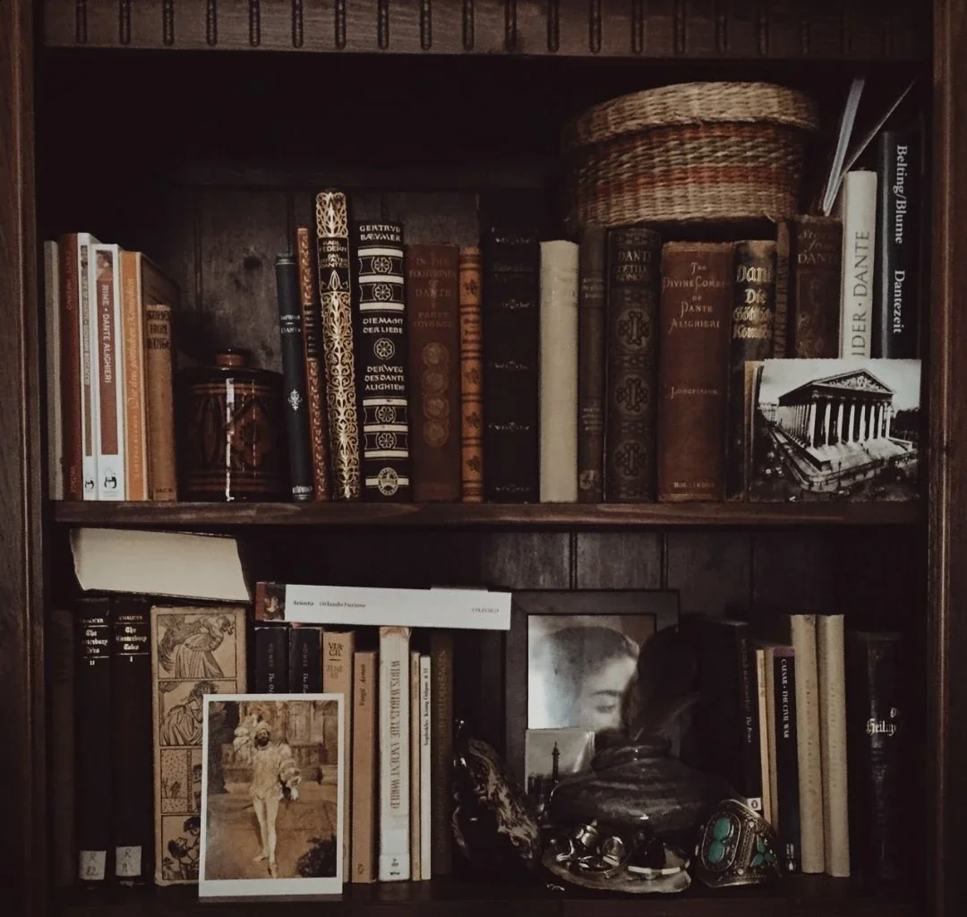 A dark wooden bookshelf filled with books, photographs, and decorative items including baskets, a framed picture of a woman, and a photo of a dog.