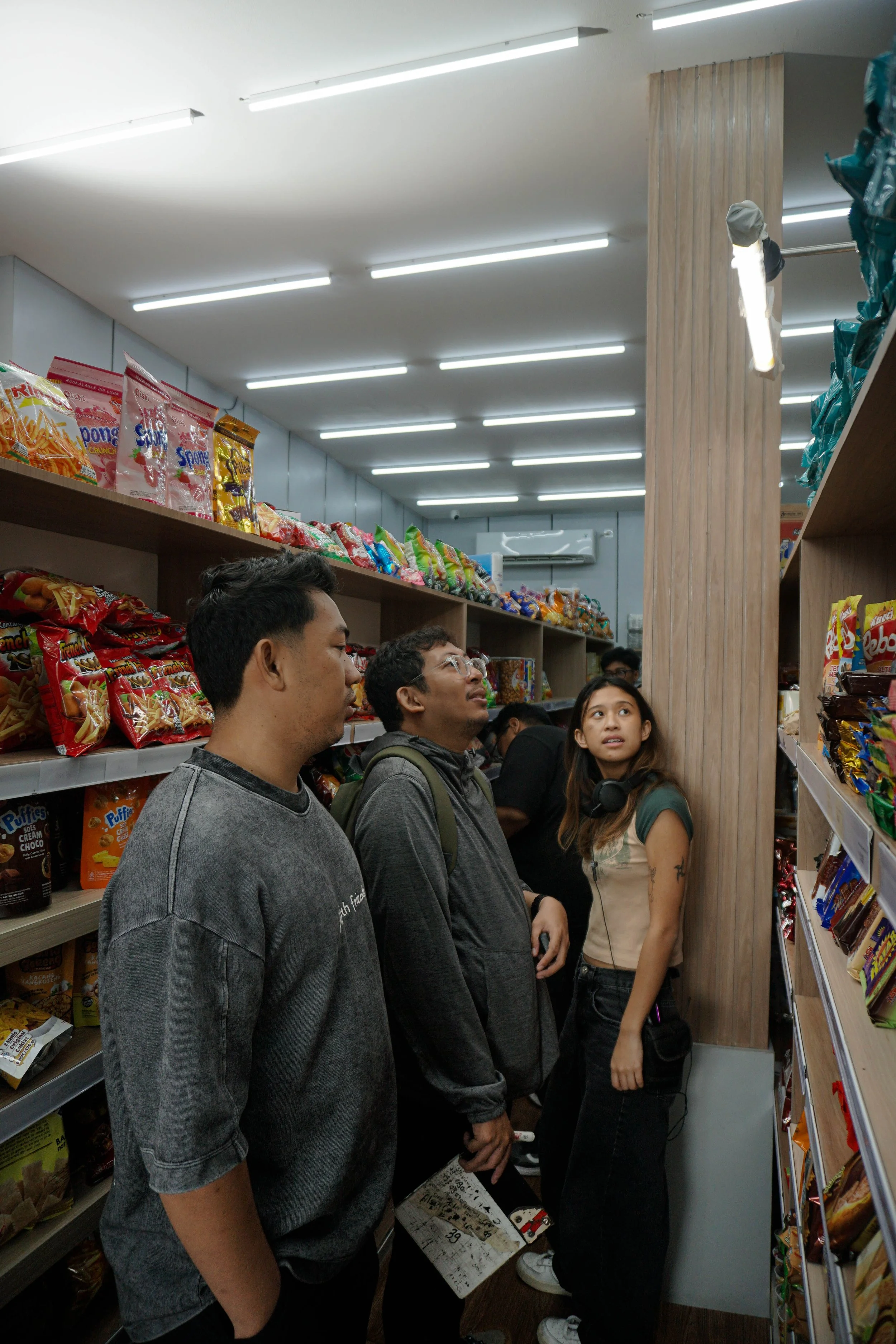 People shopping in an aisle of a snack store, with shelves stocked with various chips and snacks.