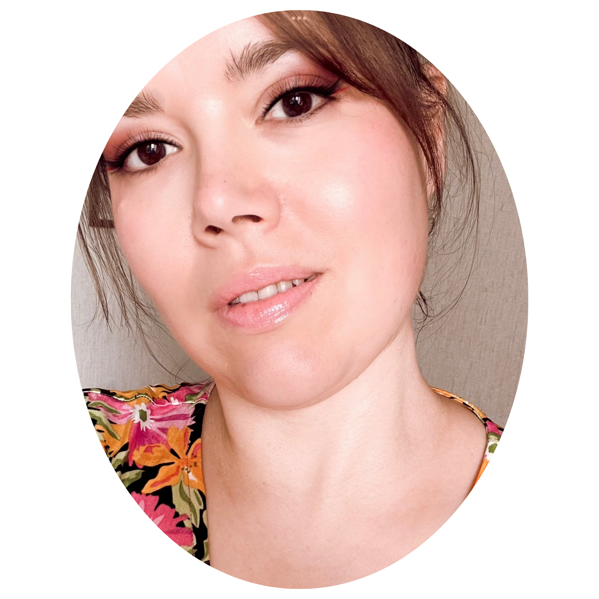 Portrait d'une femme avec des cheveux bruns, maquillage léger, portant un vêtement à motifs floraux, sur fond neutre.