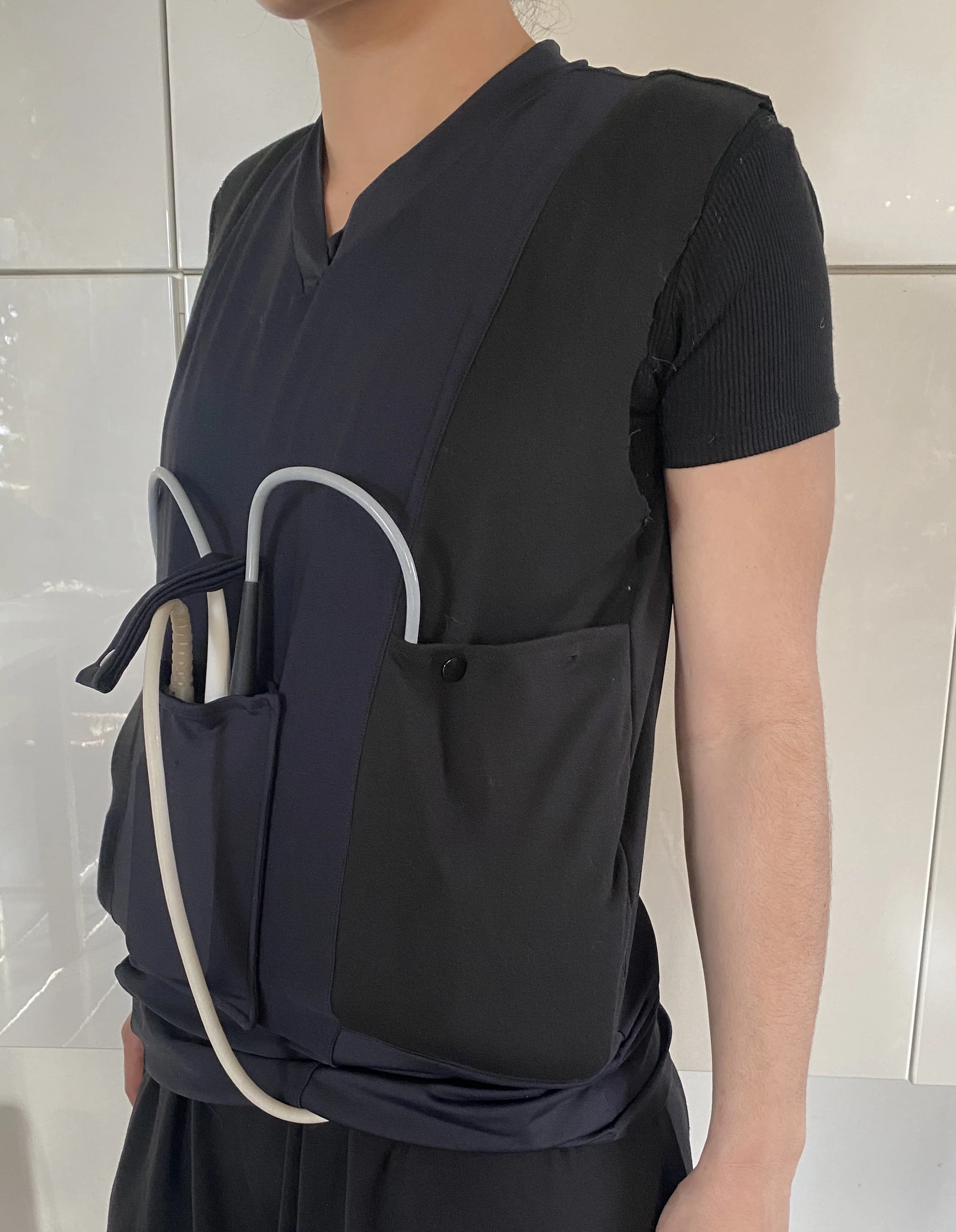 Personne portant un gilet de sauvetage noir avec des poches, se préparant pour un exercice ou une activité nautique.
