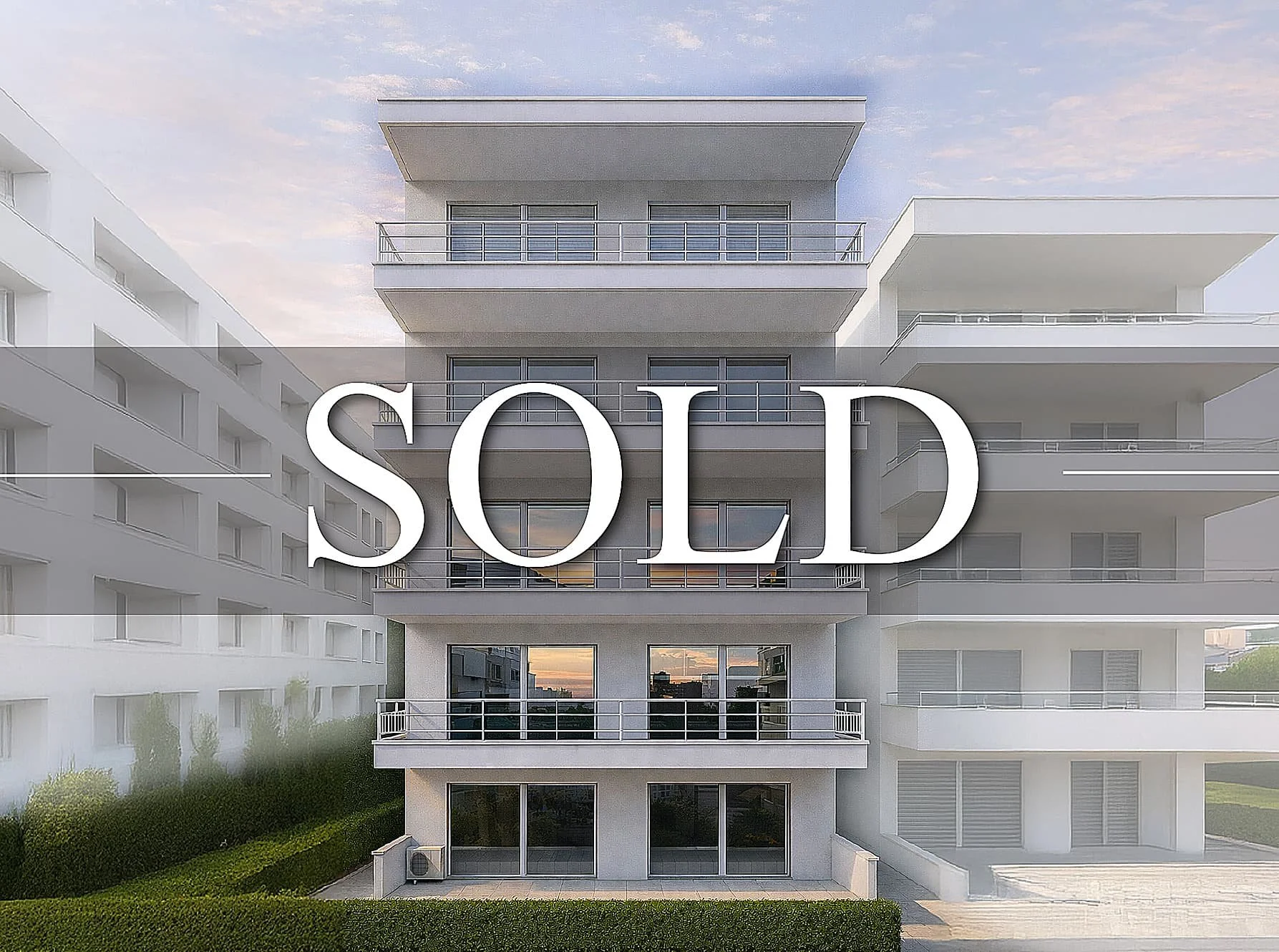In front of a five-story white apartment building, the word SOLD is digitally added in large white letters.