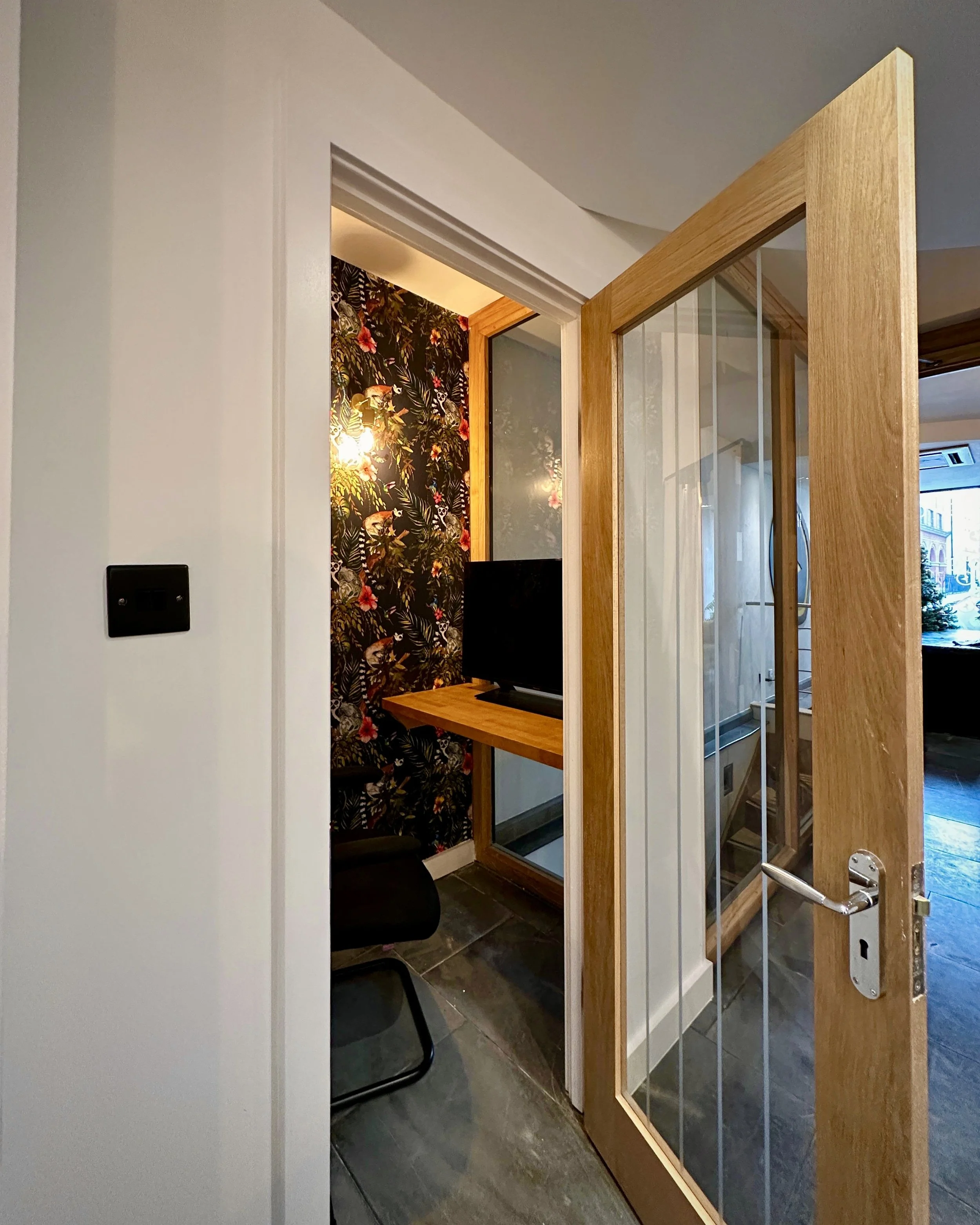 A phone booth with its door open revealing a chair and desk inside, as part of the Conservatory meeting room.