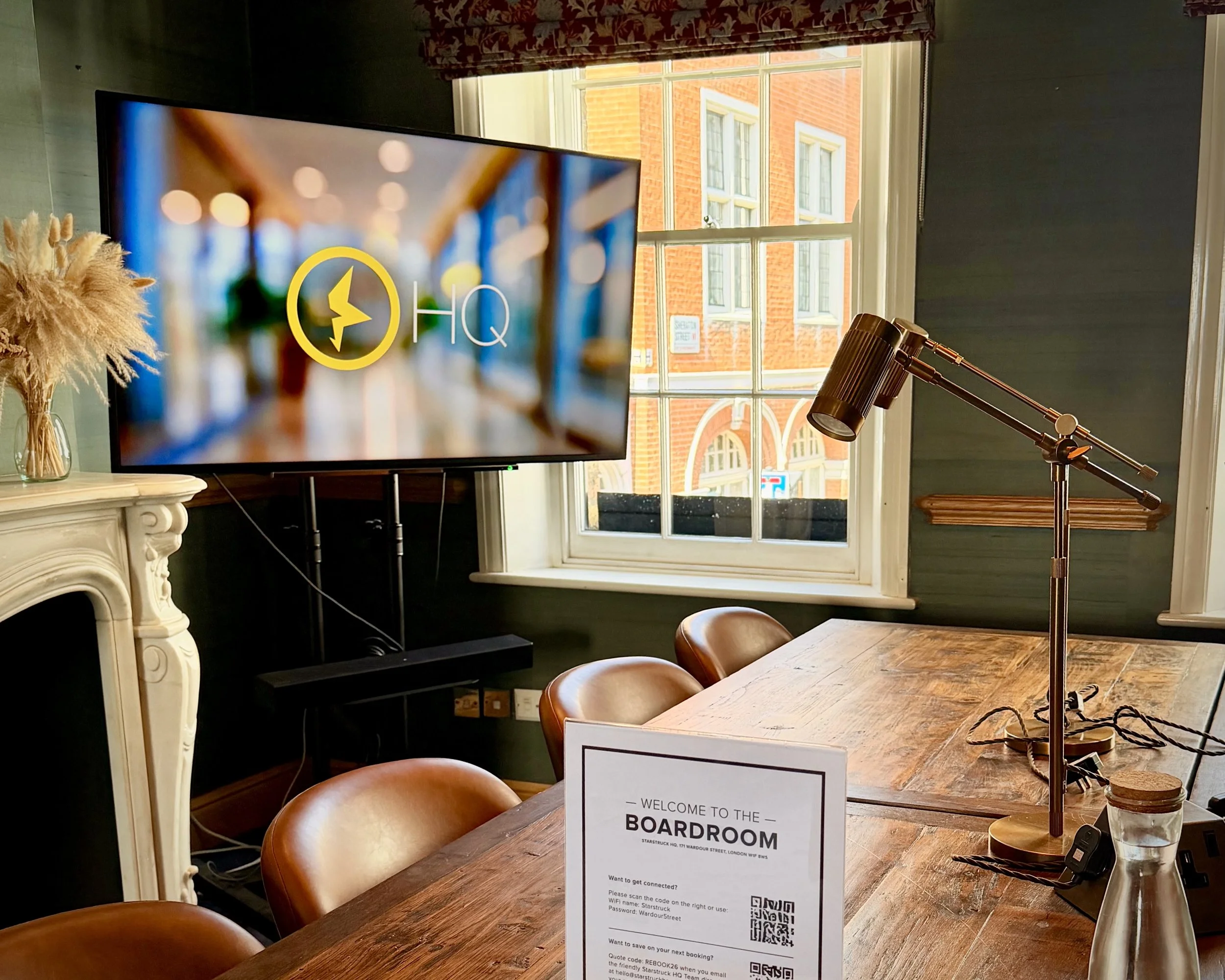 A meeting room in Soho, London with a big oak boardroom table with brown chairs and big windows looking over Wardour Street
