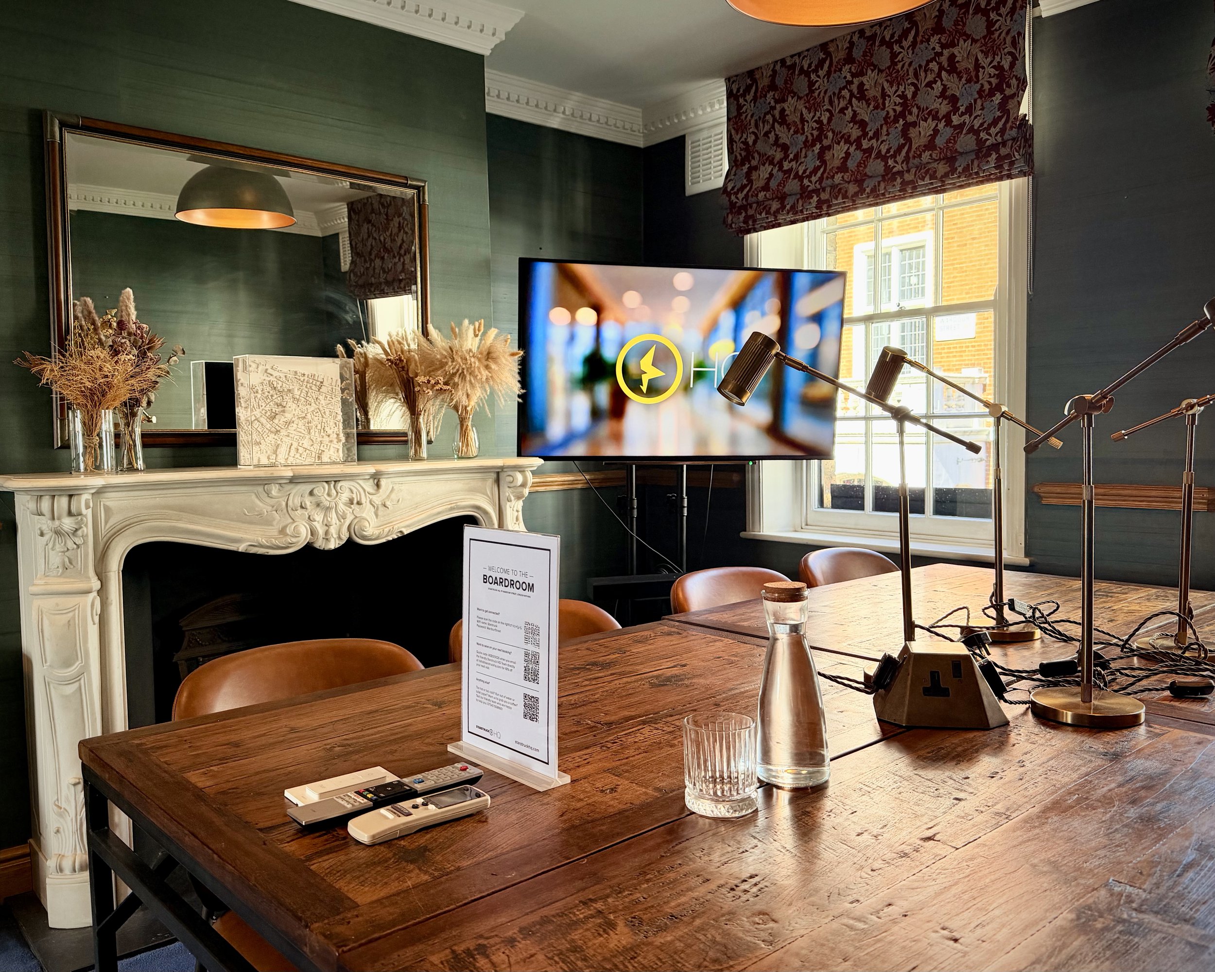 A meeting room in Soho, London with a big oak boardroom table with brown chairs and big windows looking over Wardour Street