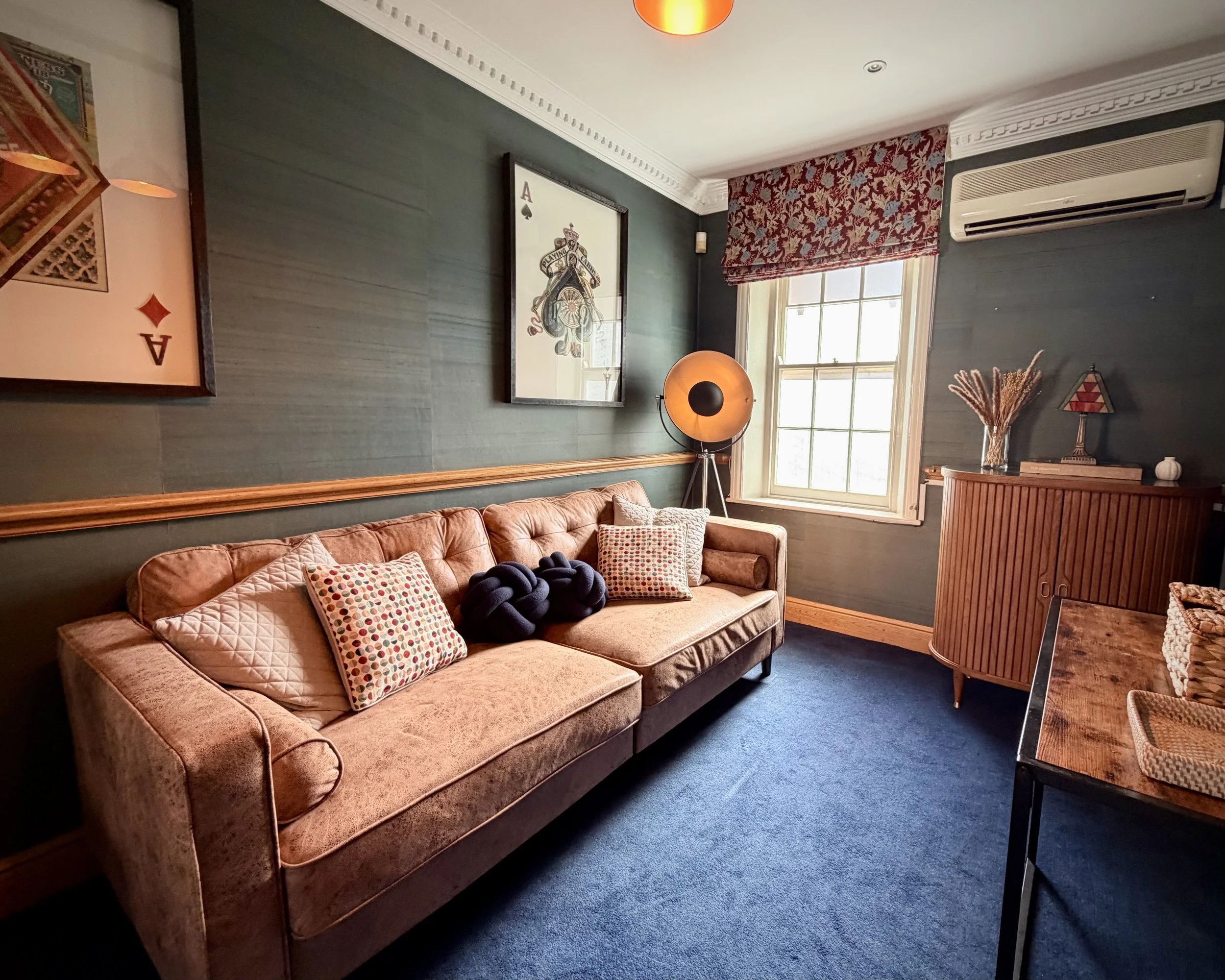 A meeting room in Soho, London, with a big chestnut sofa and artwork on the walls as well as a large drinks cabinet