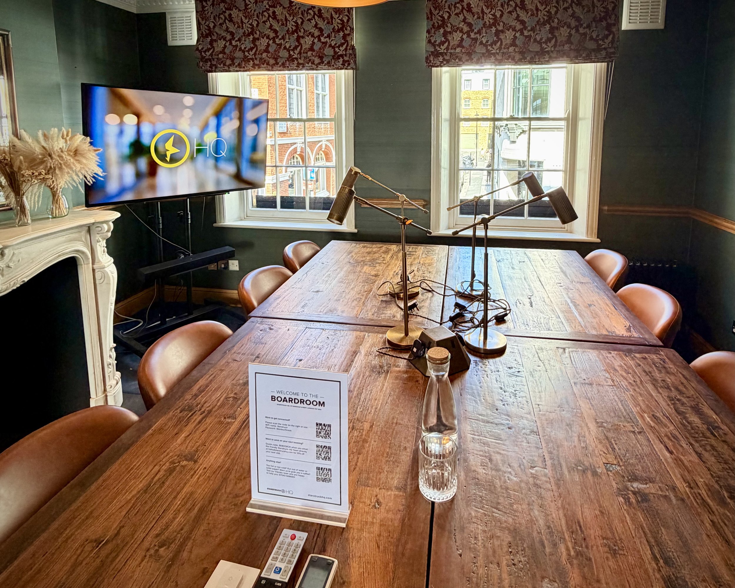 A meeting room in Soho, London with a big oak boardroom table with brown chairs and big windows looking over Wardour Street