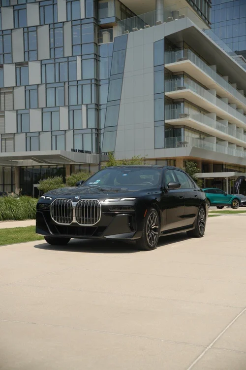 Professional chauffeur beside black BMW executive sedan for luxury transportation in Dallas