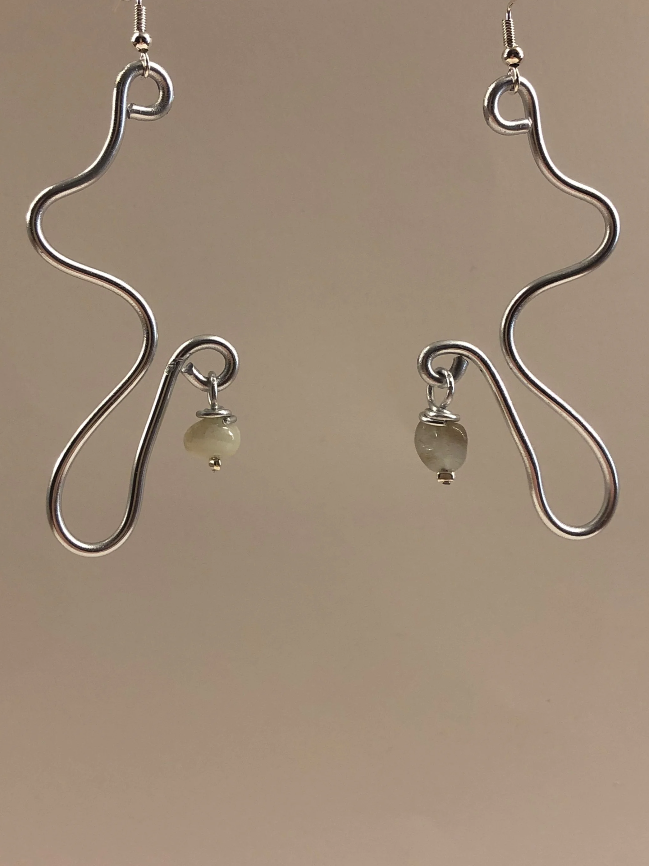 Silver earrings with wavy design and small round beads hanging at the bottom.