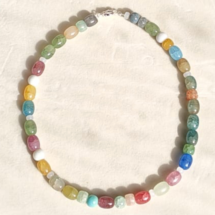 Colorful beaded necklace with various shades of pastel and bright beads arranged in a circle on a light background.