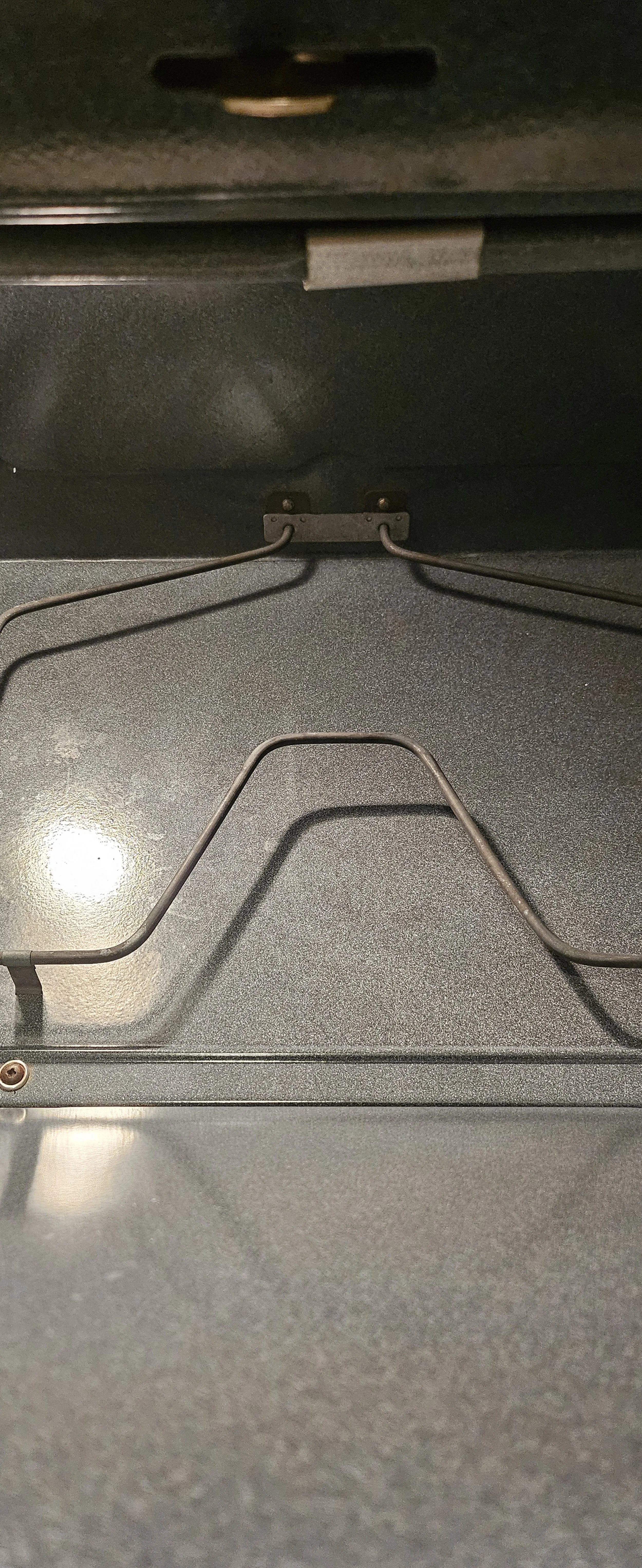 Inside view of an oven with heating elements and metal racks