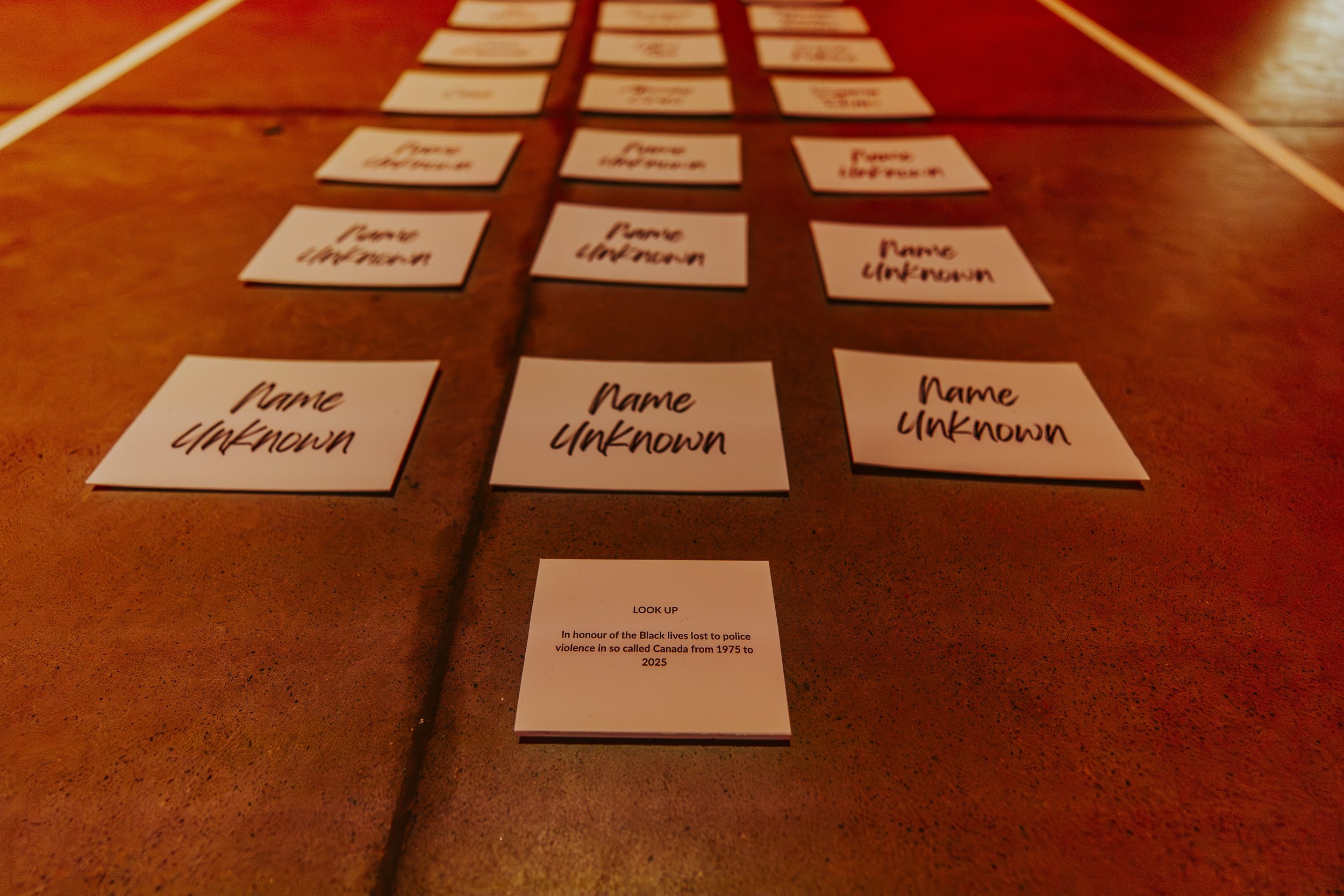 Cards laid out on a table with the words "Name Unknown" and a card with a message honoring Black lives lost to police violence from 1975 to 2025.