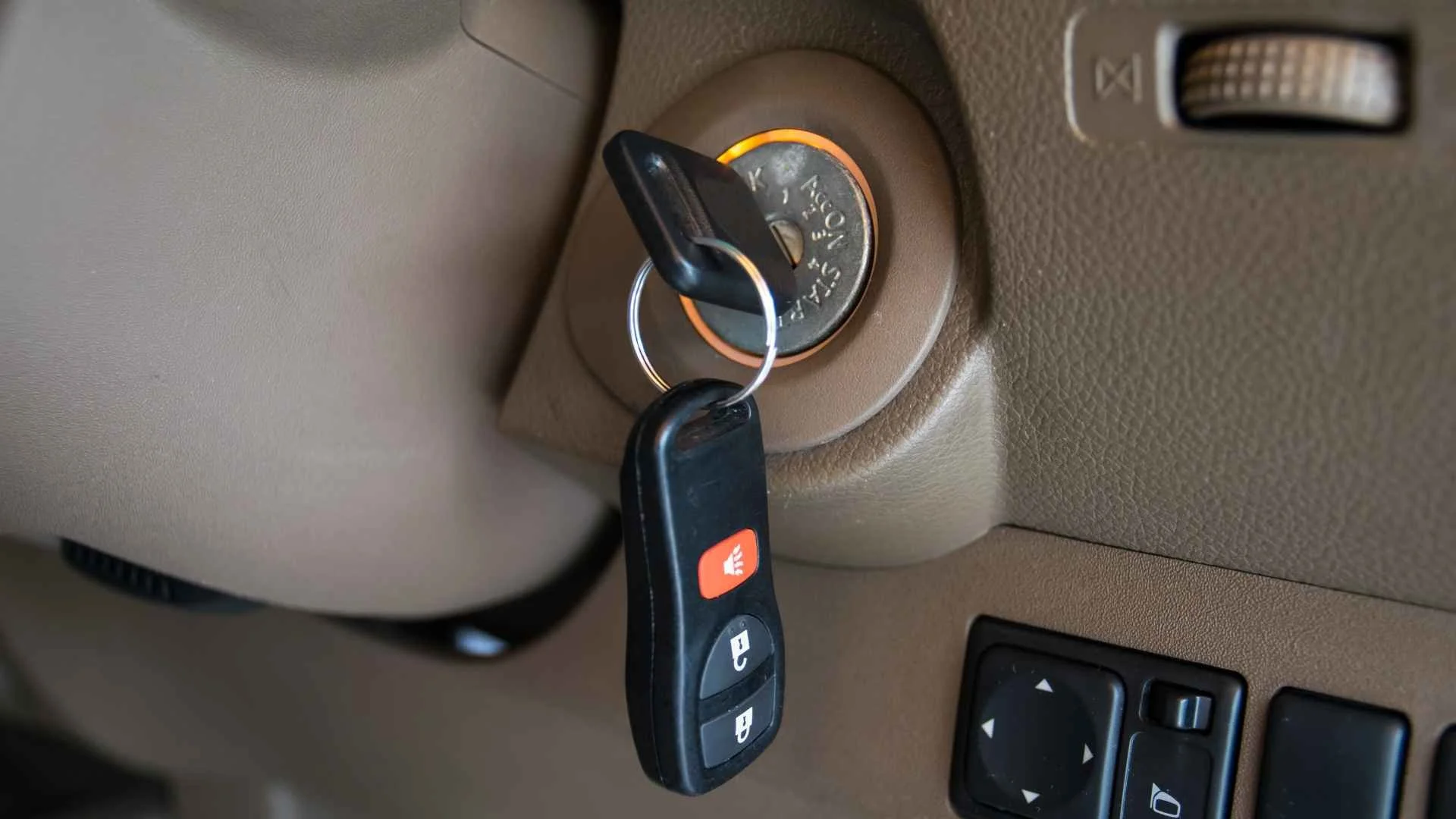 Car key inserted into ignition switch in a vehicle, with lights indicating the engine status.