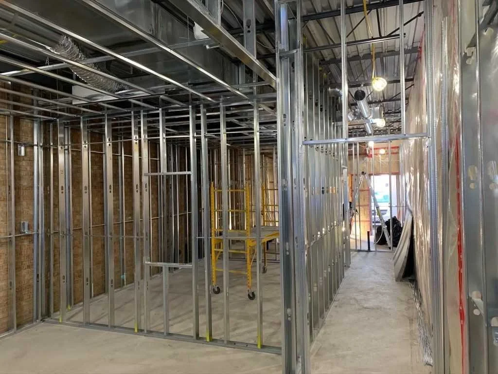 Interior of a building under construction with metal framing for walls and ceiling.