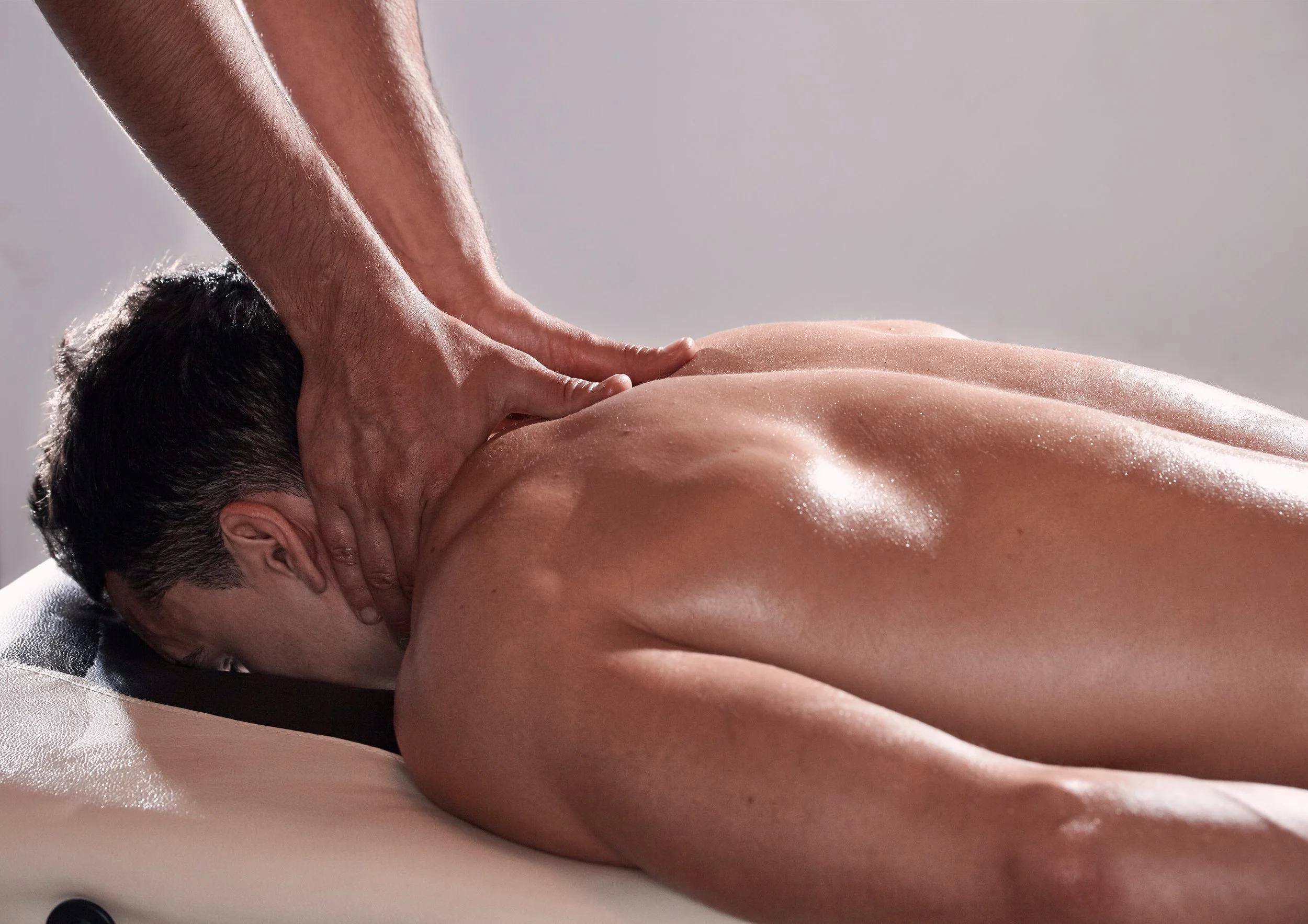 A man receiving a back massage while lying face down on a massage table.