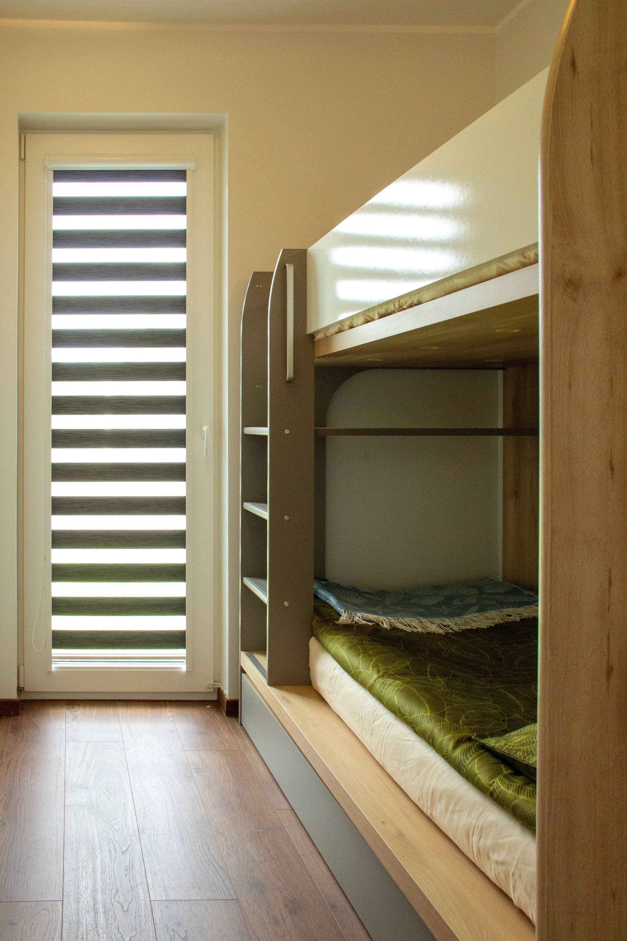 A room with a bunk bed and a door with horizontal black and white striped blinds.