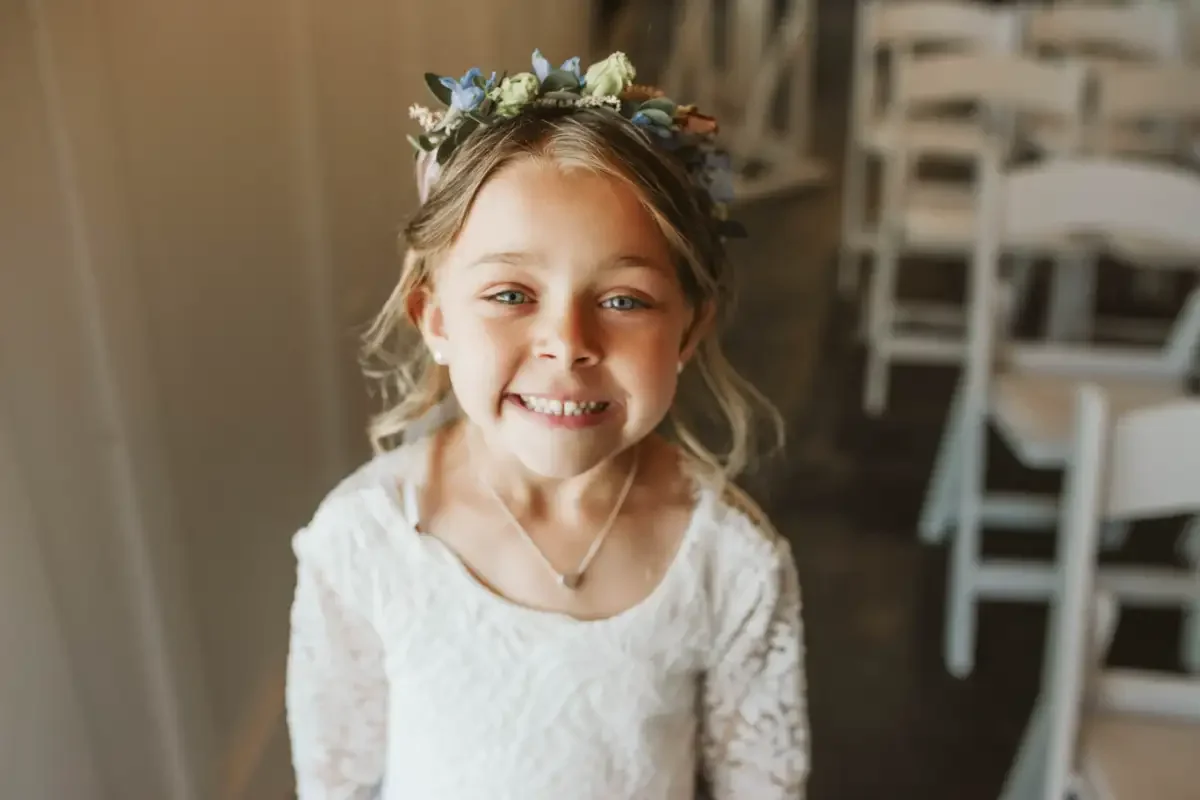 flower-girl-portrait-smiling-candid-photo-sycamore-tree-wedding.webp