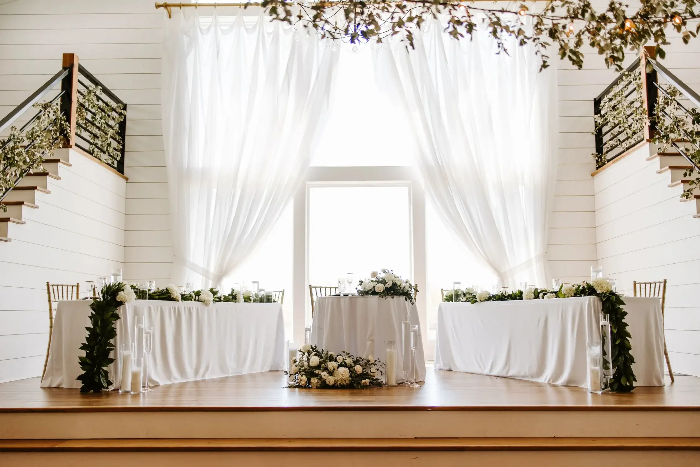 elevated-white-head-table-stage-florals-emerson-fields-floral-stories.webp