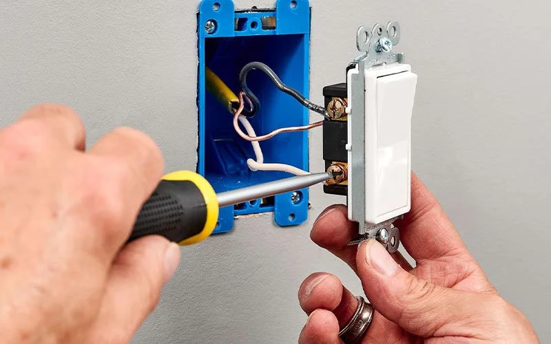 Elektriker montiert einen neuen Lichtschalter in einer Wanddose