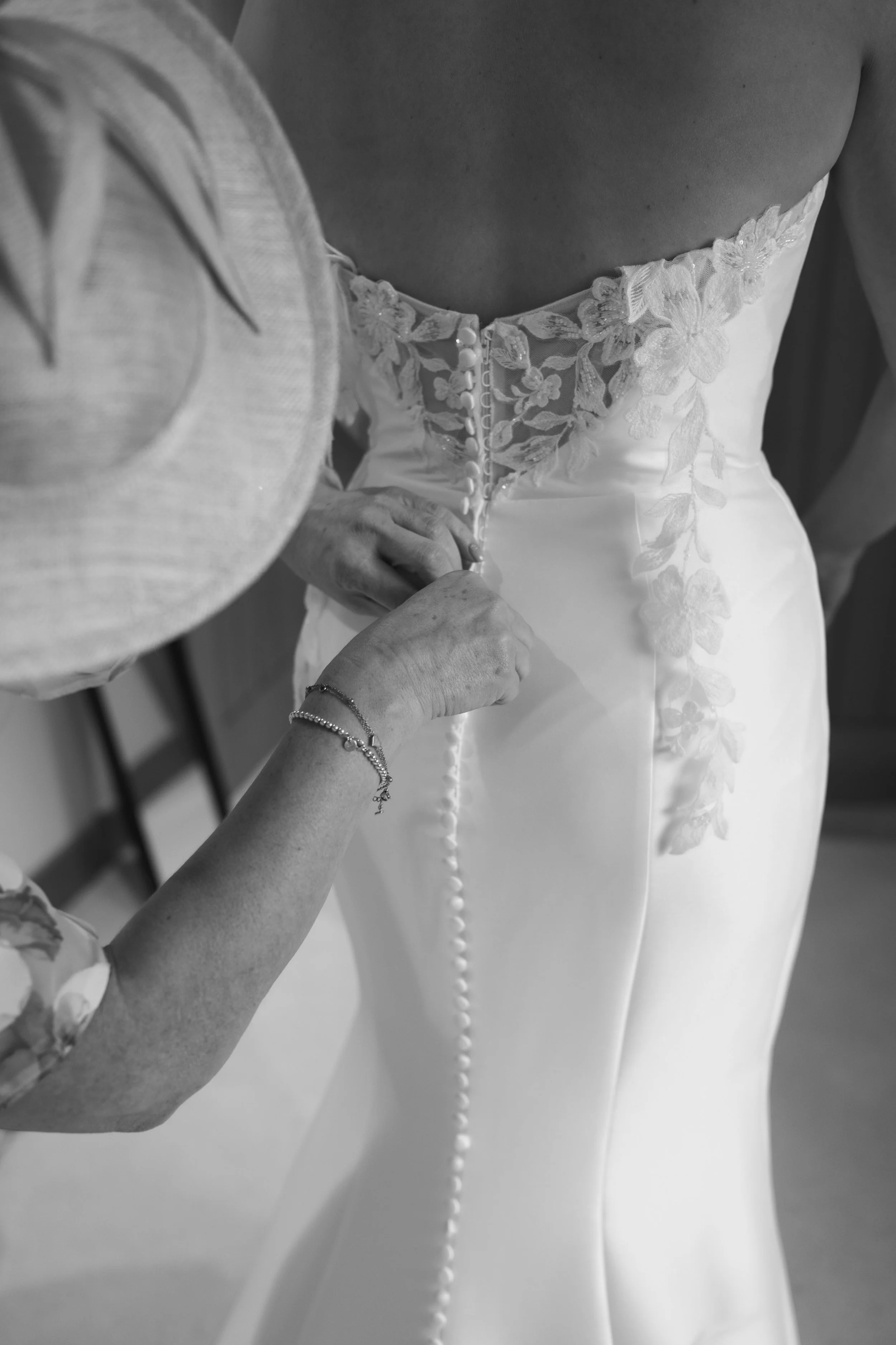 A bride and groom share a kiss in front of a historic stone building with gothic windows and ornate architectural details, during their wedding.