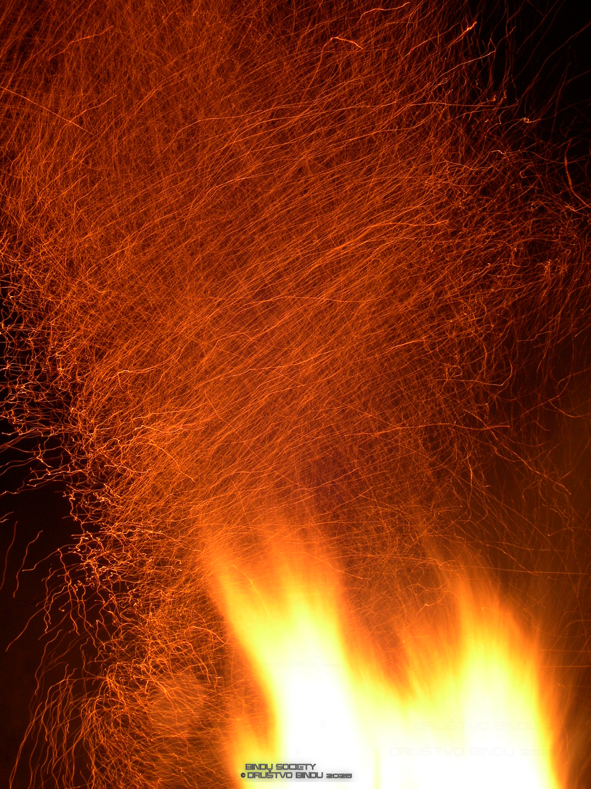 Close-up of a fire with sparks flying in the air at night.