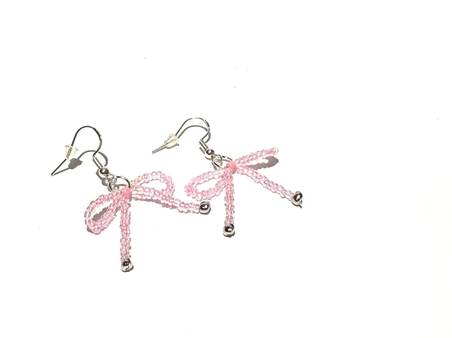 Pink beaded earrings with bow-shaped designs on a white background.