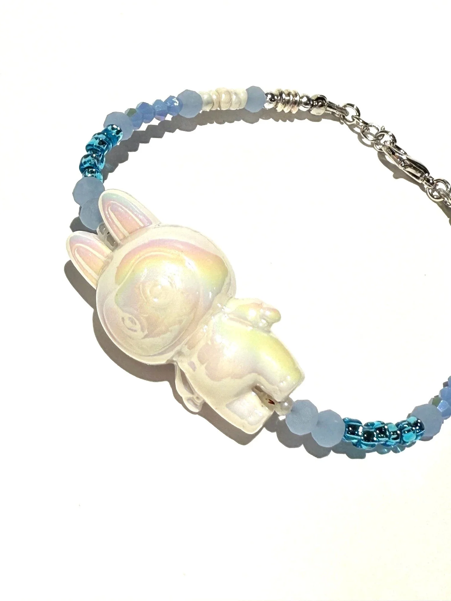 A beaded bracelet with a central white rabbit figurine and small pastel blue beads, featuring an adjustable chain and clasp.