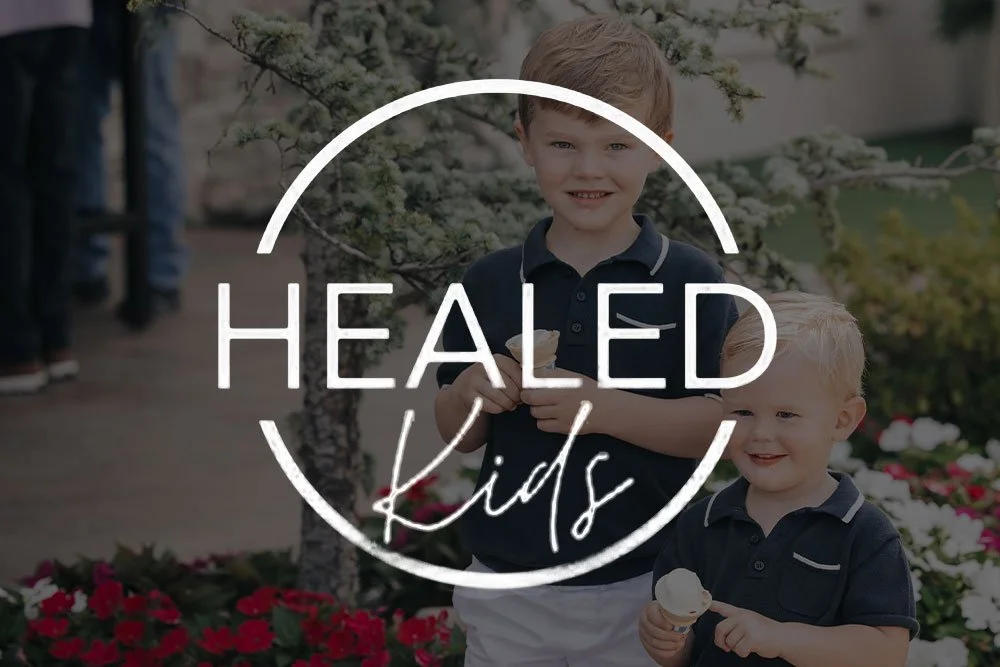 Two young boys smiling and holding ice cream cones outdoors with flowers and trees in the background, overlaid with the text 'Healed Kids'.